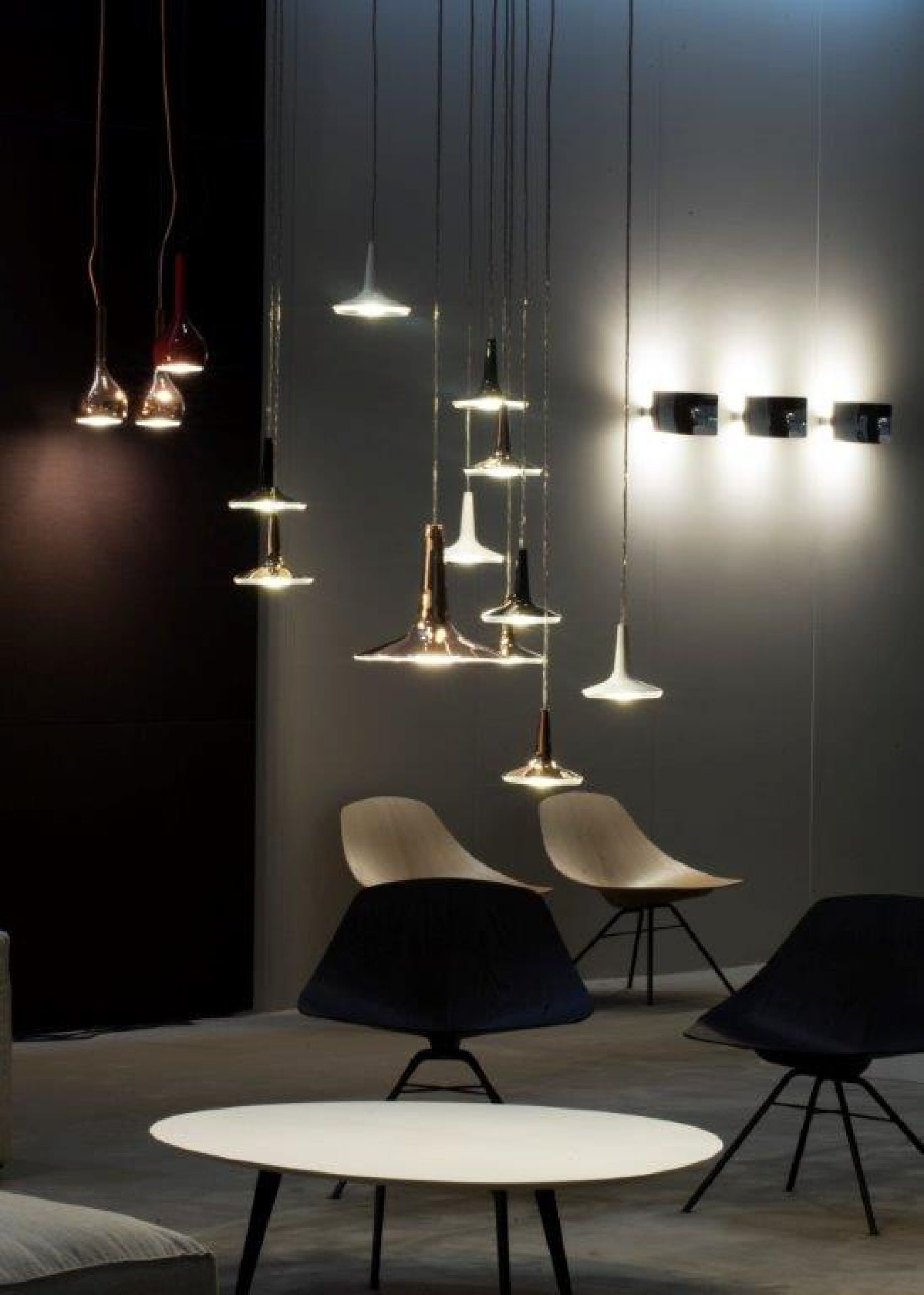 Kin LED Pendelleuchte von Oluce: Moderne Hängeleuchten in verschiedenen Formen und Farben über einem Wohnbereich.