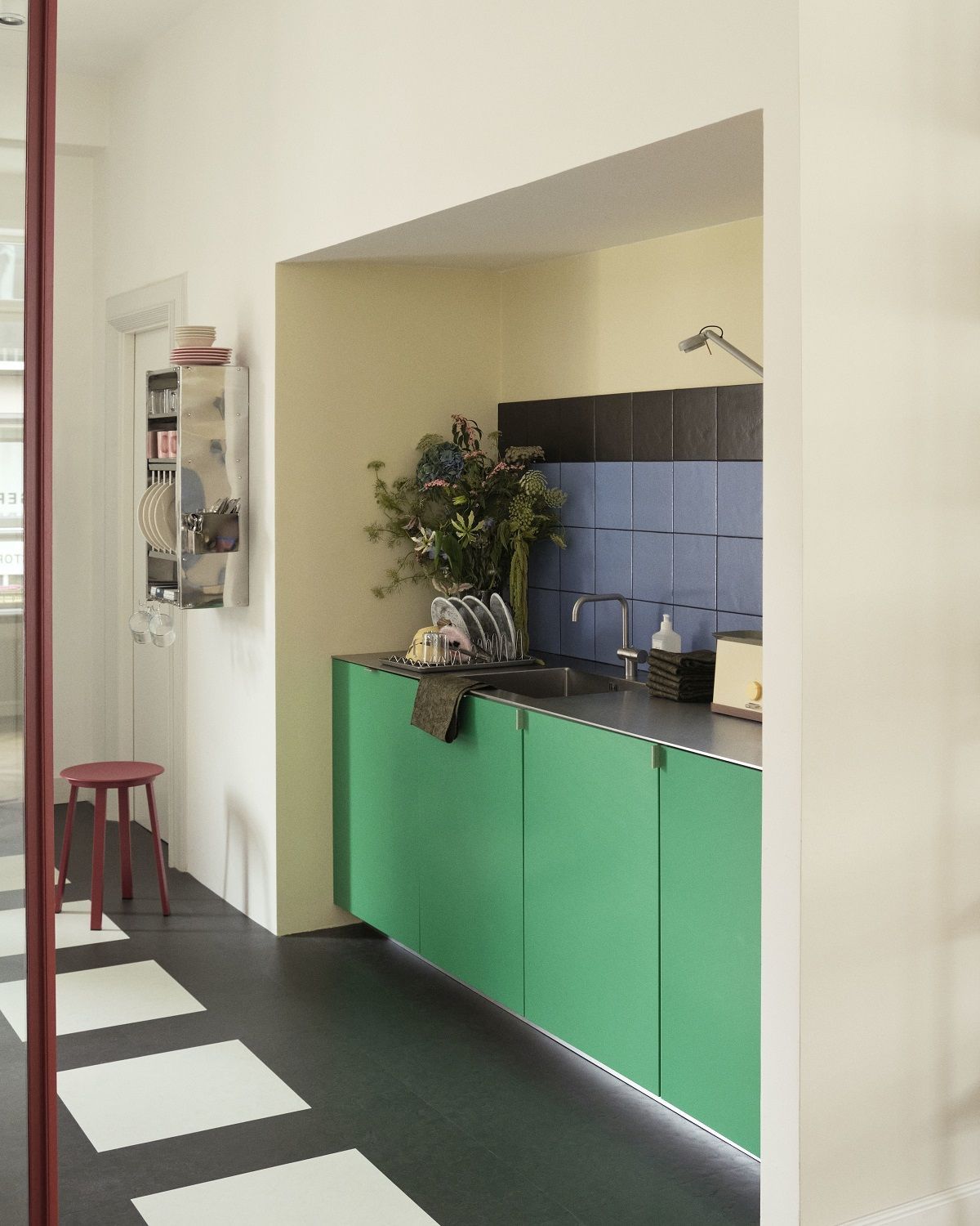 Roter Revolver Stool Hocker von Hay in moderner Küche mit grünen Schränken.