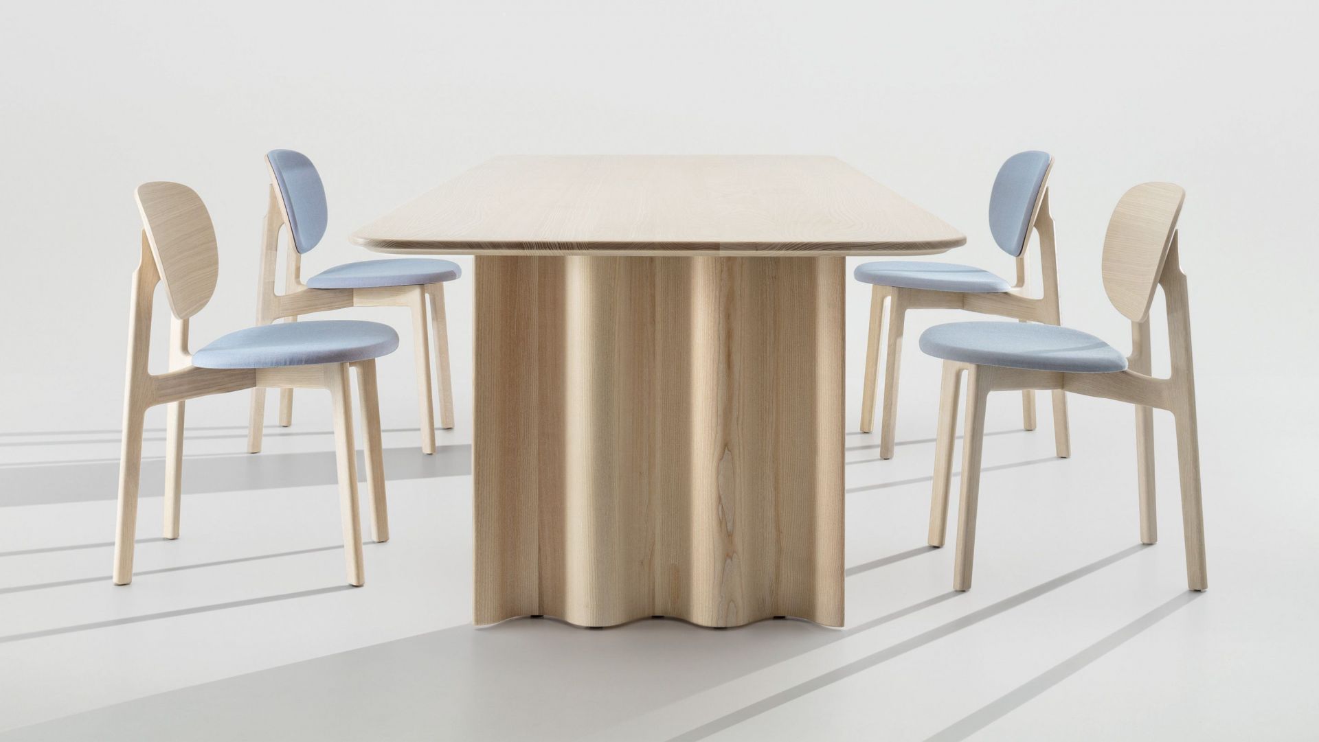 Curtain Tisch: Rechteckiger Esstisch aus hellem Holz mit passenden Stühlen und blauen Sitzflächen.