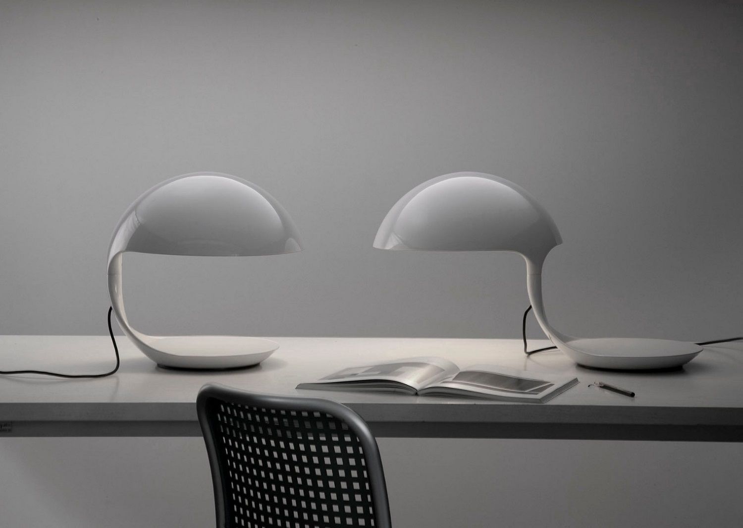 Zwei weiße Cobra Tischleuchten von Martinelli Luce auf einem Schreibtisch mit Buch.