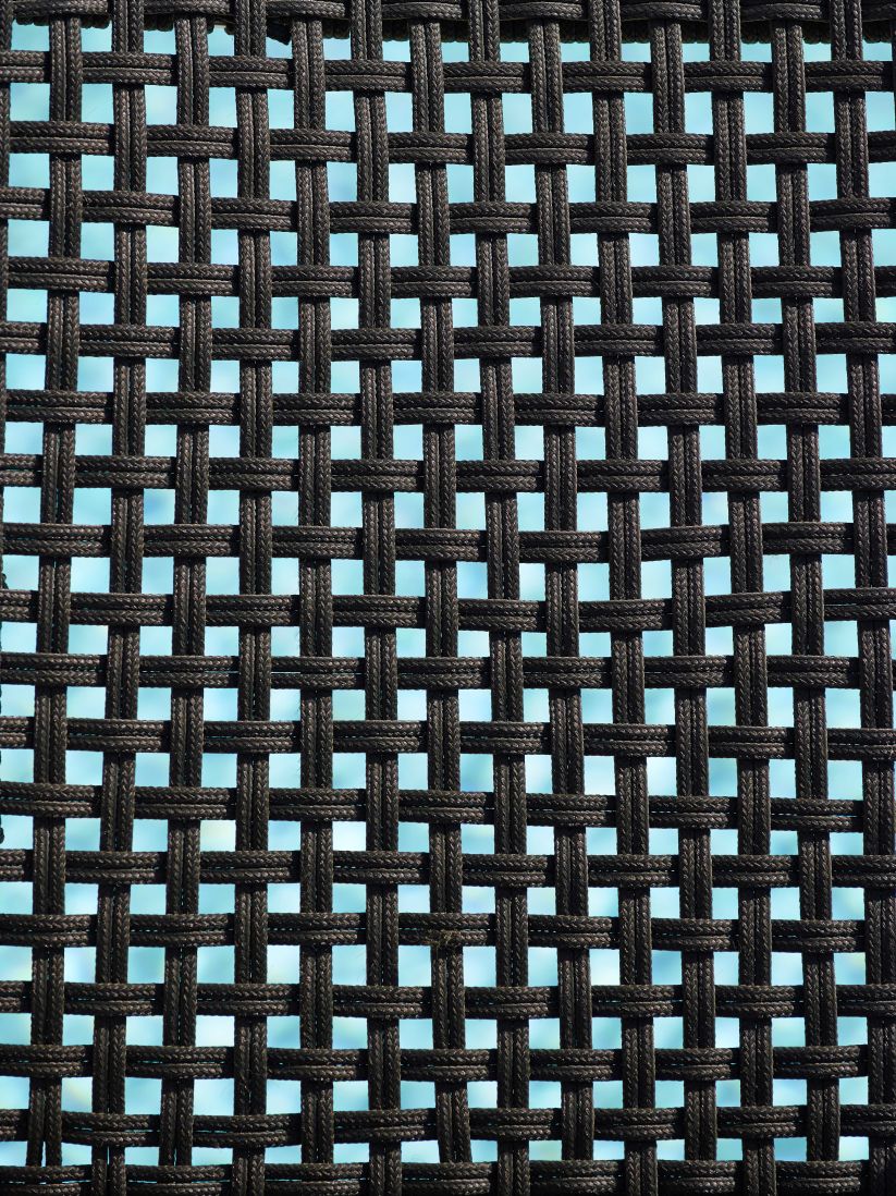 Detailaufnahme des Cane-Line Straw Armlehnstuhls: Geflochtene, schwarze Sitzfläche für Outdoor-Möbel.