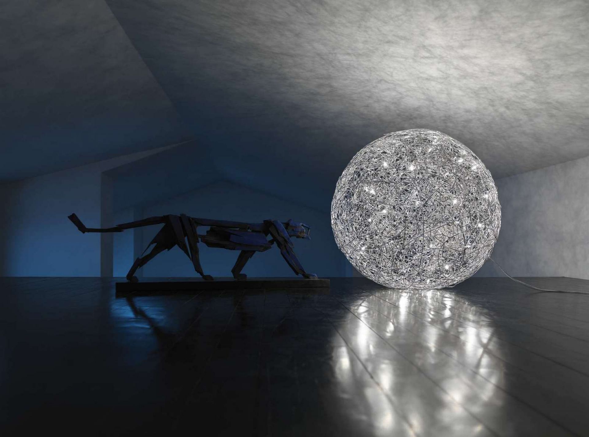 Fil de Fer Bodenleuchte von Catellani & Smith: Kugelförmige Drahtleuchte mit warmem Licht neben Panther-Skulptur.