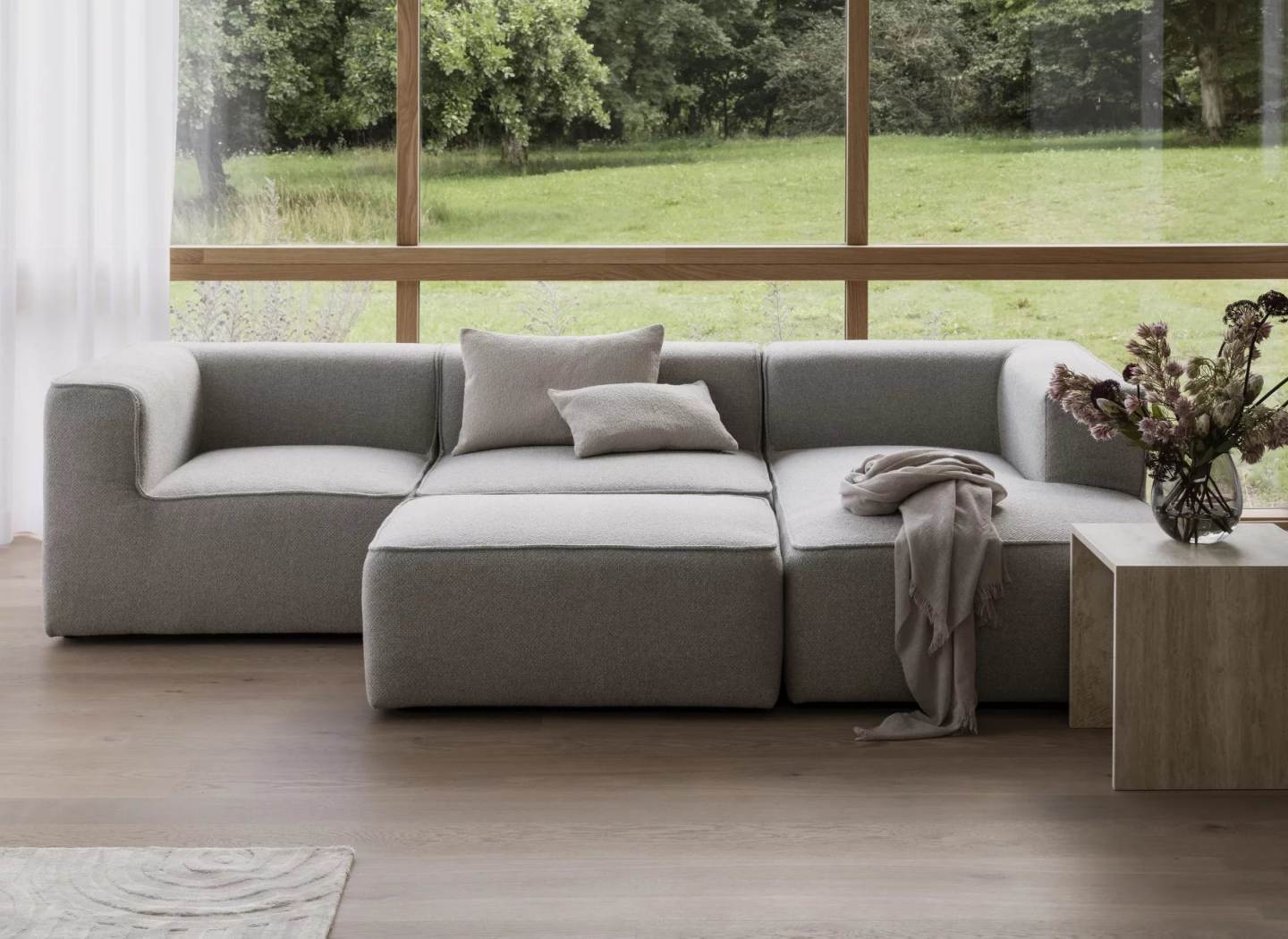 Blomus Uzu Rug Teppich im Wohnzimmer mit grauem Sofa, Kissen und Holzboden.