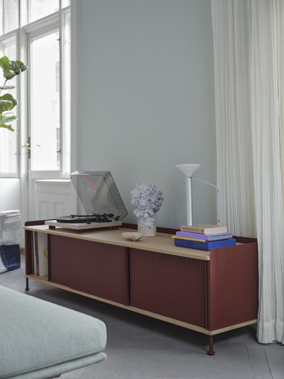 Enfold Sideboard Low von Muuto in Rotbraun mit Schiebetüren und Plattenspieler im Wohnzimmer.