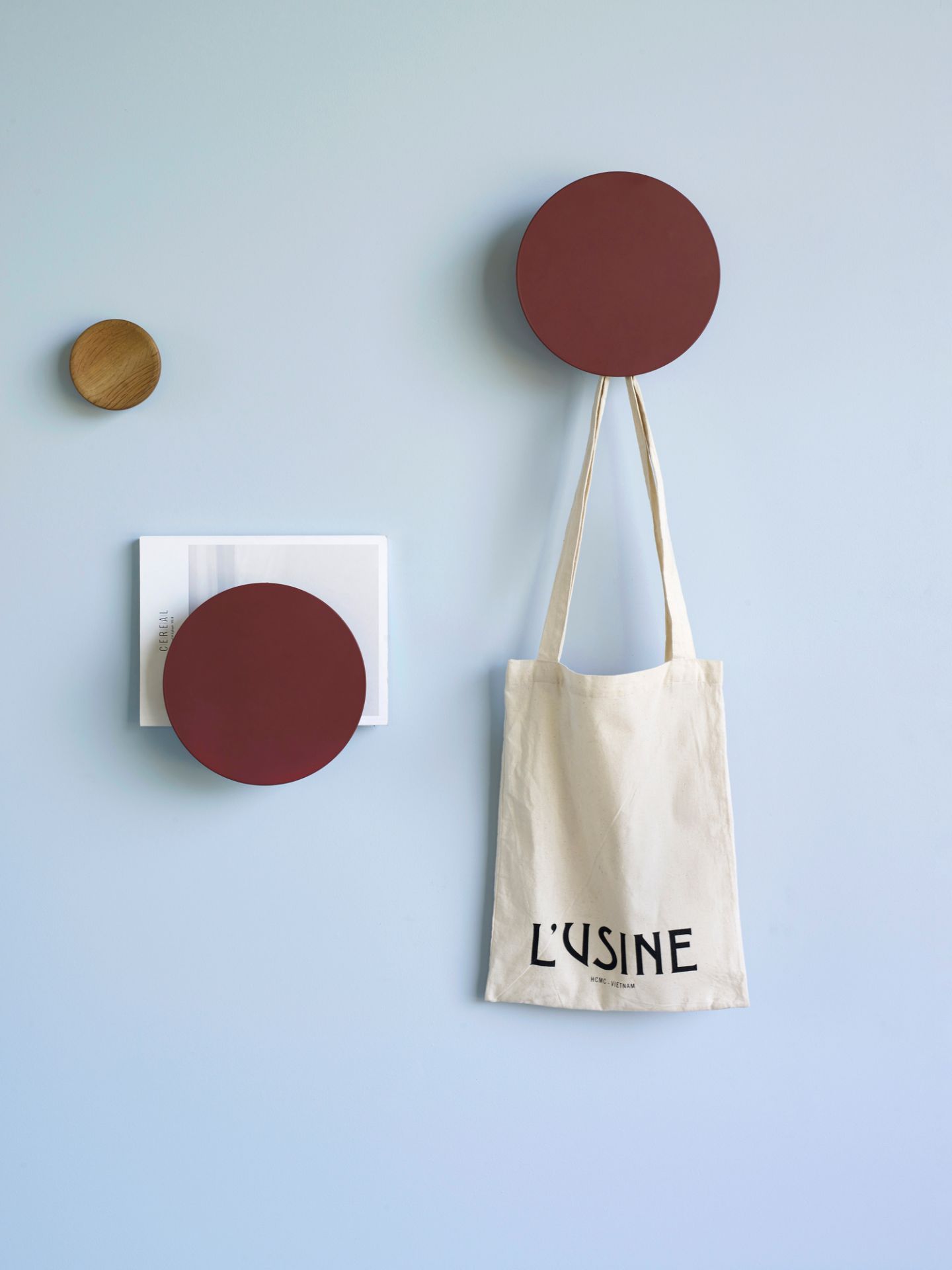 Wanddekoration mit rotem Metall Knopf Magazinhalter, Zeitschriften und Stoffbeutel an hellblauer Wand.