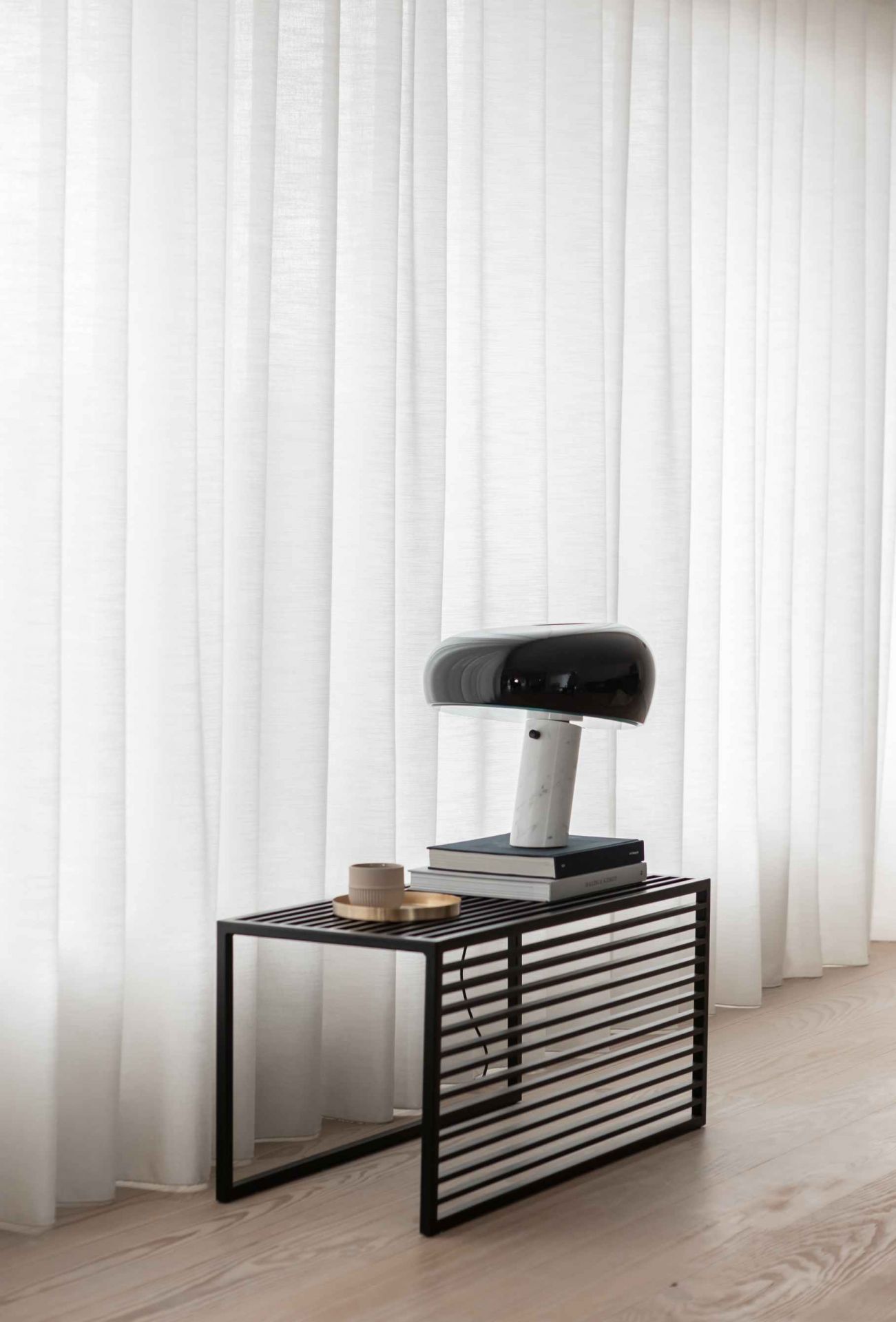 Element Bench Bank novoform: Schwarze Bank mit Lamellen, darauf Lampe, Bücher und Tasse.