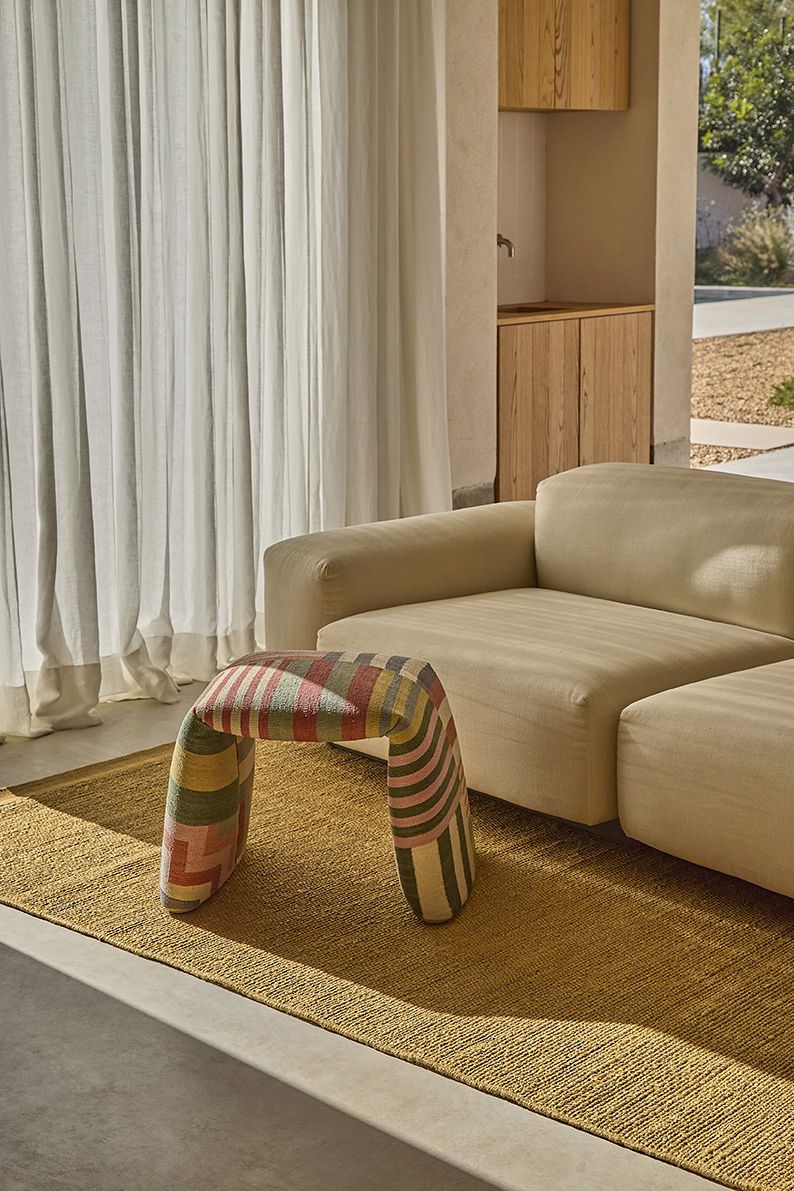 Nanimarquina Bank: Gepolsterte Sitzbank mit farbigem Muster, passend zum Teppich und Sofa.