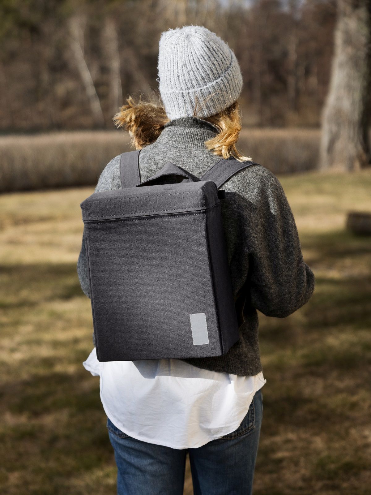 Frau mit grauem Urban Thermal Backpack Rucksack von Design House Stockholm im Outdoor-Bereich.