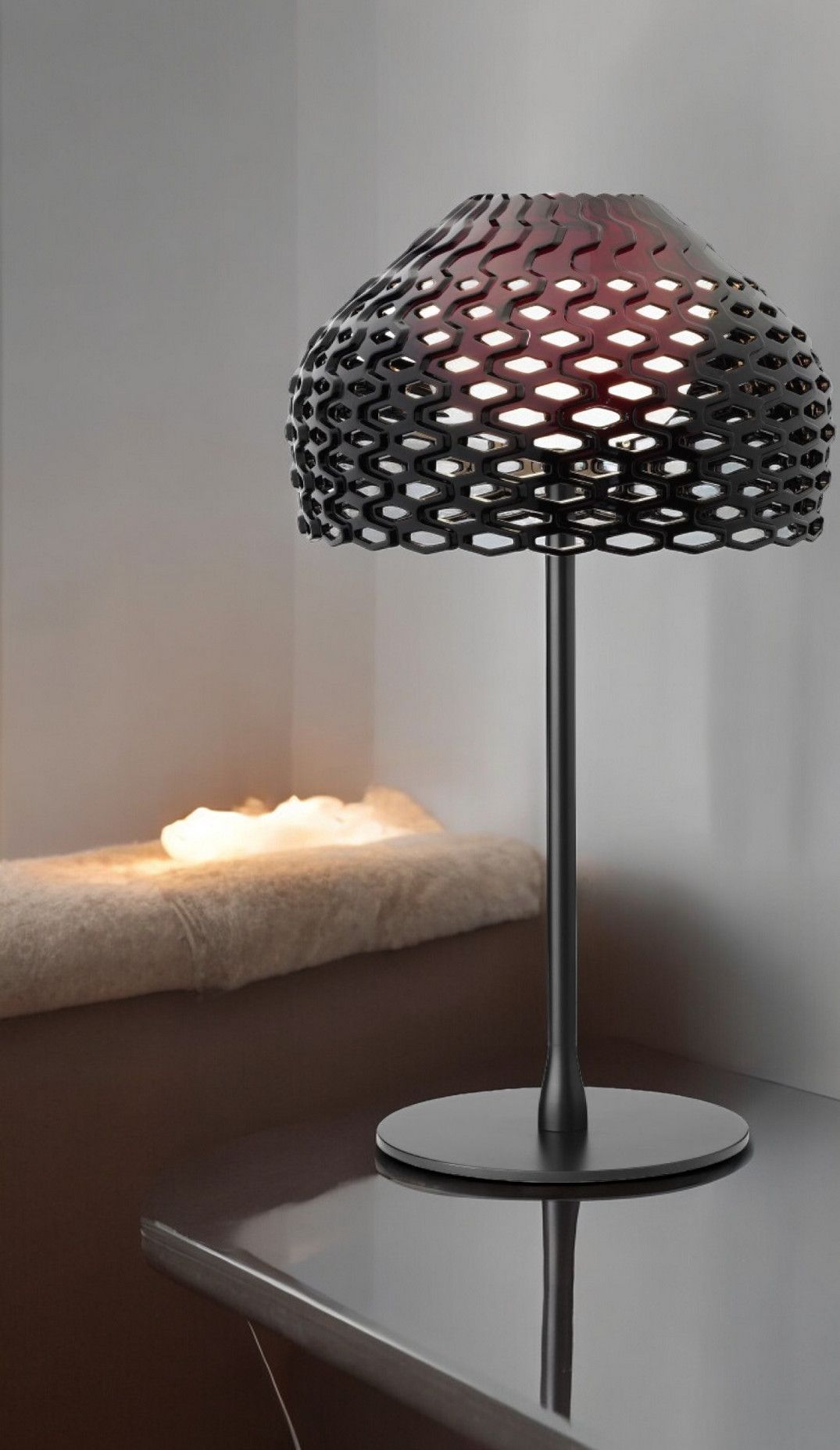 Schwarze Flos Tatou T1 Tischleuchte mit speziellem Lampenschirm-Design auf einem glänzenden Tisch.