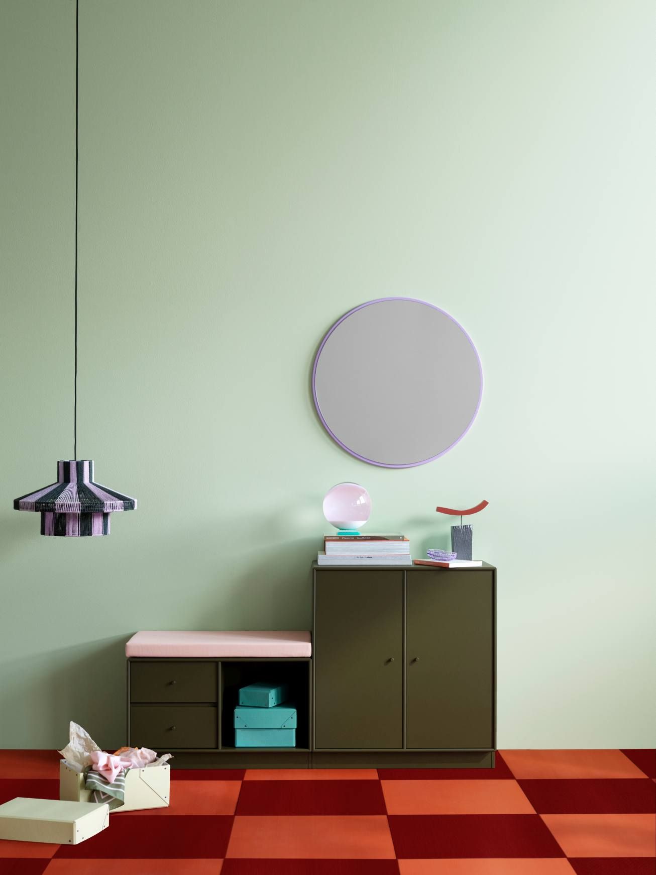 Runder Spiegel "Montana Rosehip" mit farbigem Rahmen an einer grünen Wand im Interieur.