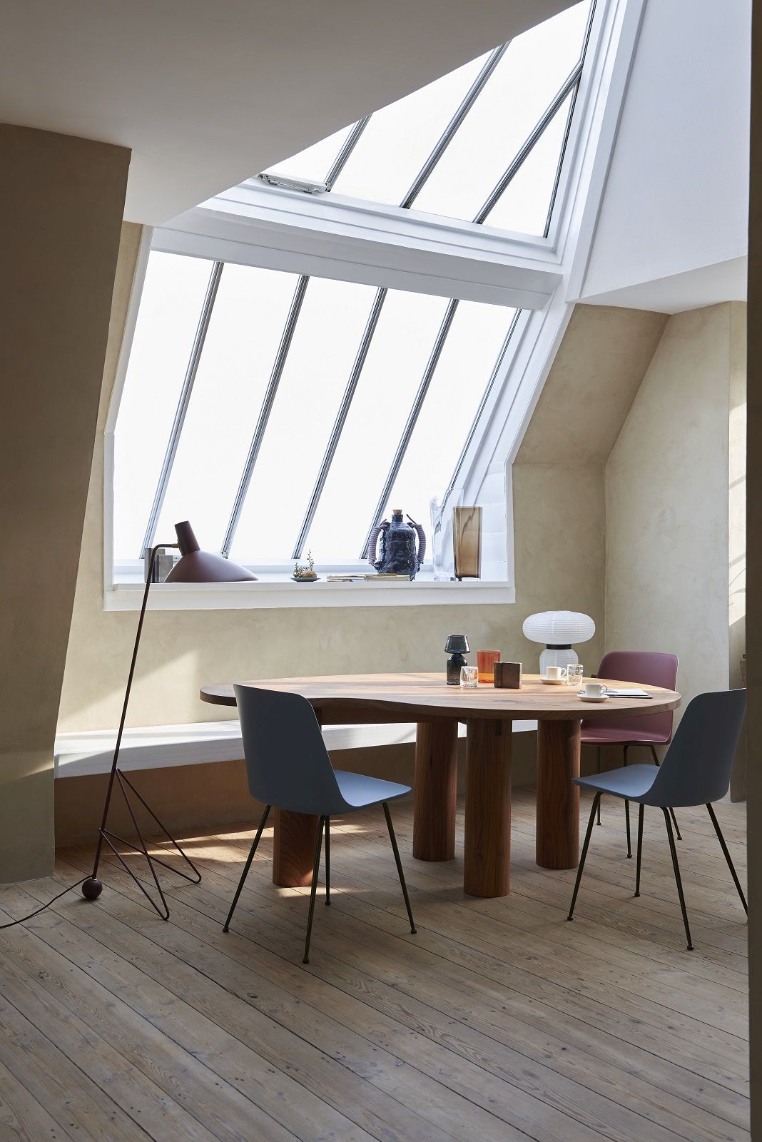 AndTradition Tripod Stehleuchte in modernem Esszimmer mit Holztisch und Stühlen unter Dachfenster.