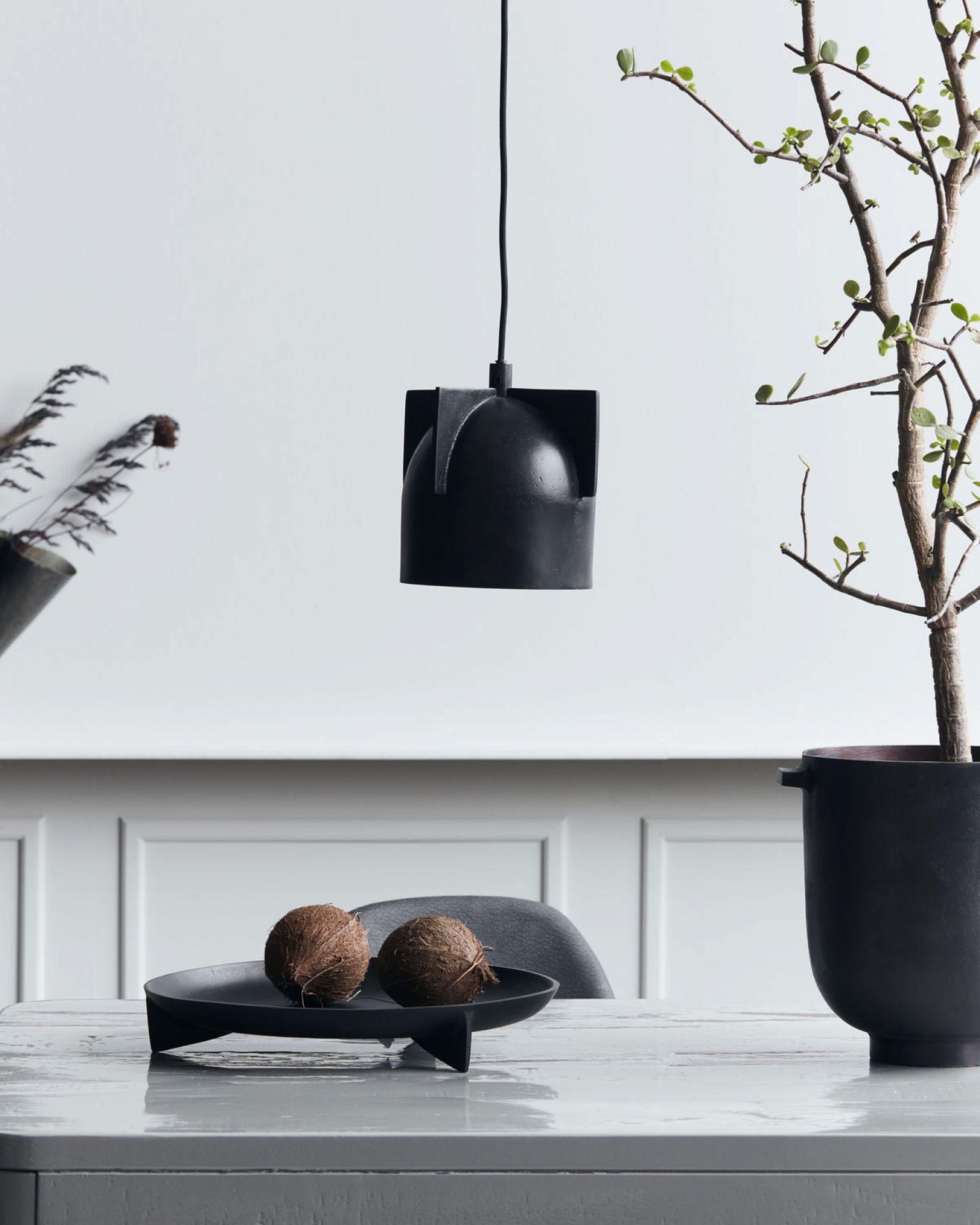 Akola Pendelleuchte von House Doctor, schwarze Hängelampe über Tisch mit Dekoration.