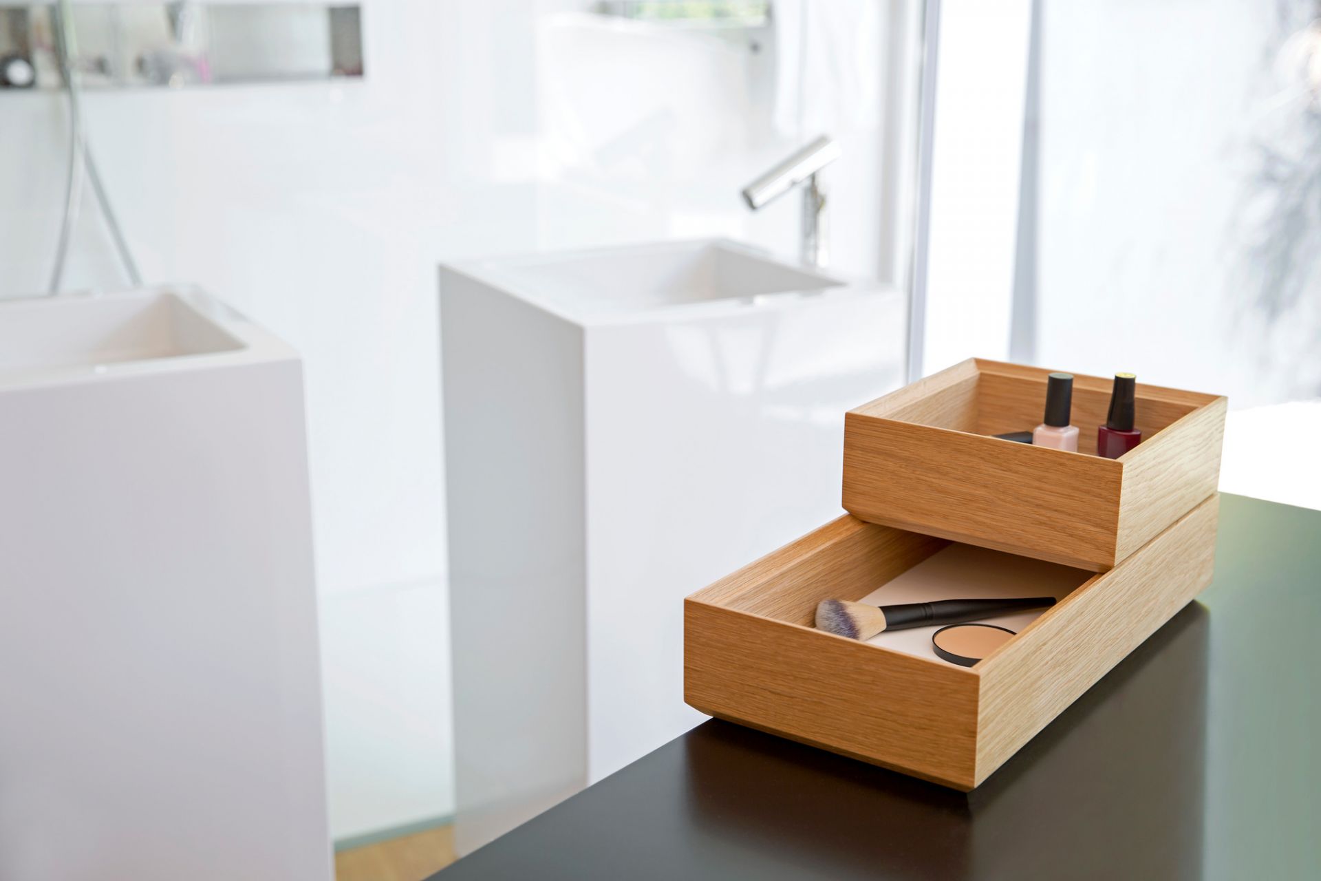 Tidy Tablett Favius 3er-Set, weiße Bad-Organizer aus Holz mit Make-up und Nagellack auf schwarzem Tisch.