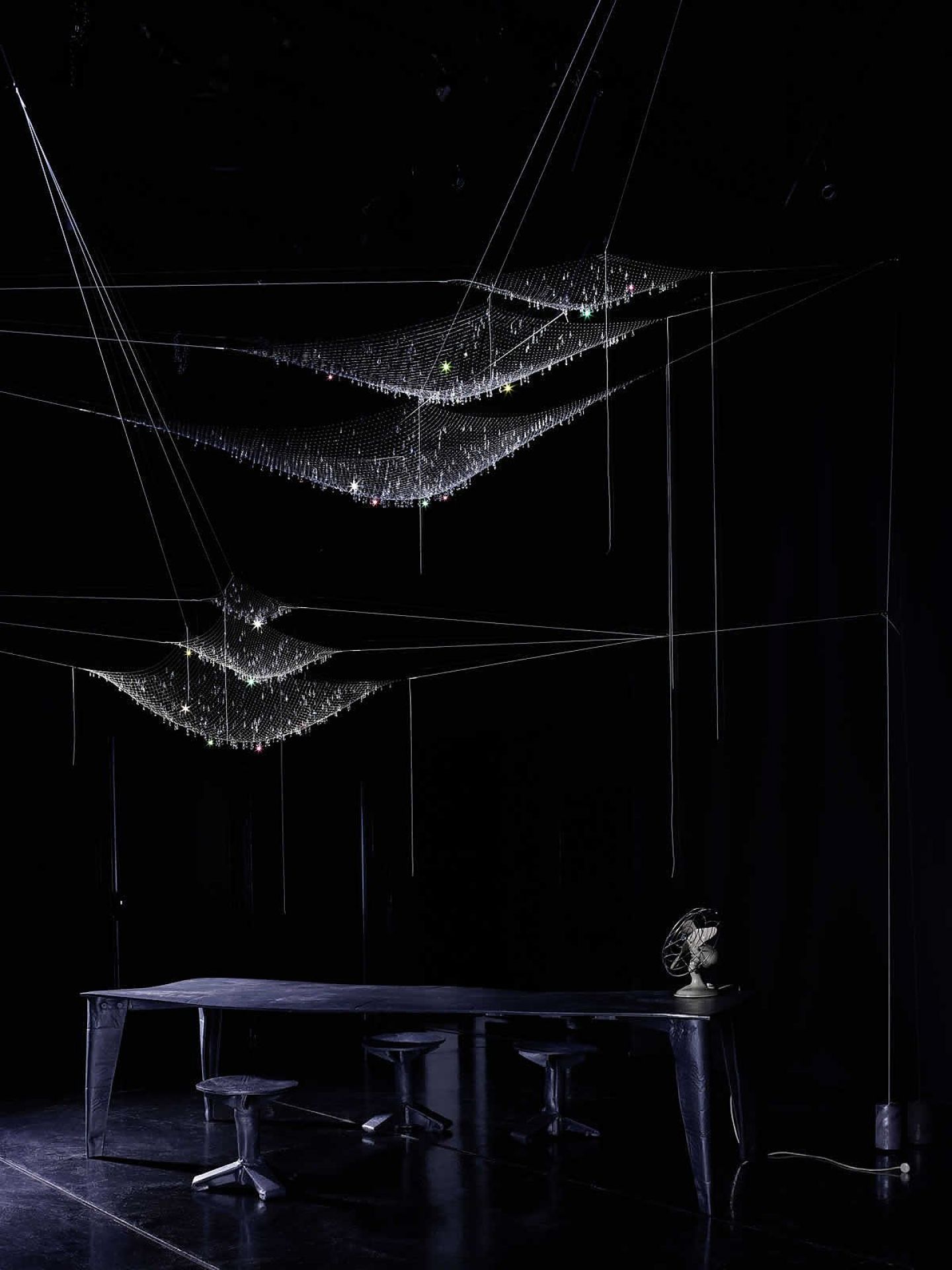 LACRIME DEL PESCATORE Pendelleuchte: Mehrere hängende, netzartige Leuchten mit glitzernden Akzenten über einem Tisch.
