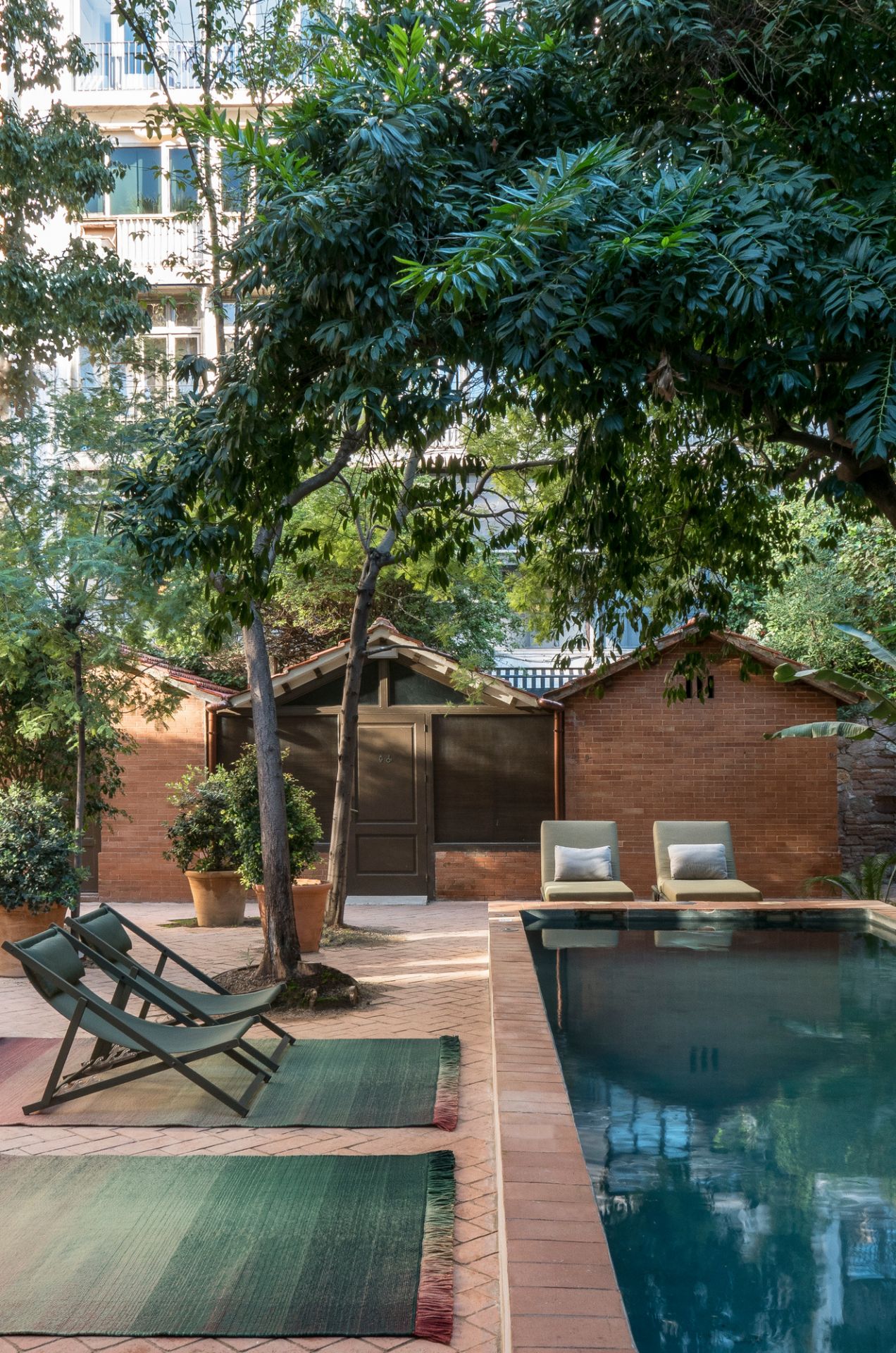 Nanimarquina Shade Outdoor Teppich 170x240 cm Palette 4 neben Pool und Liegestühlen im Garten.