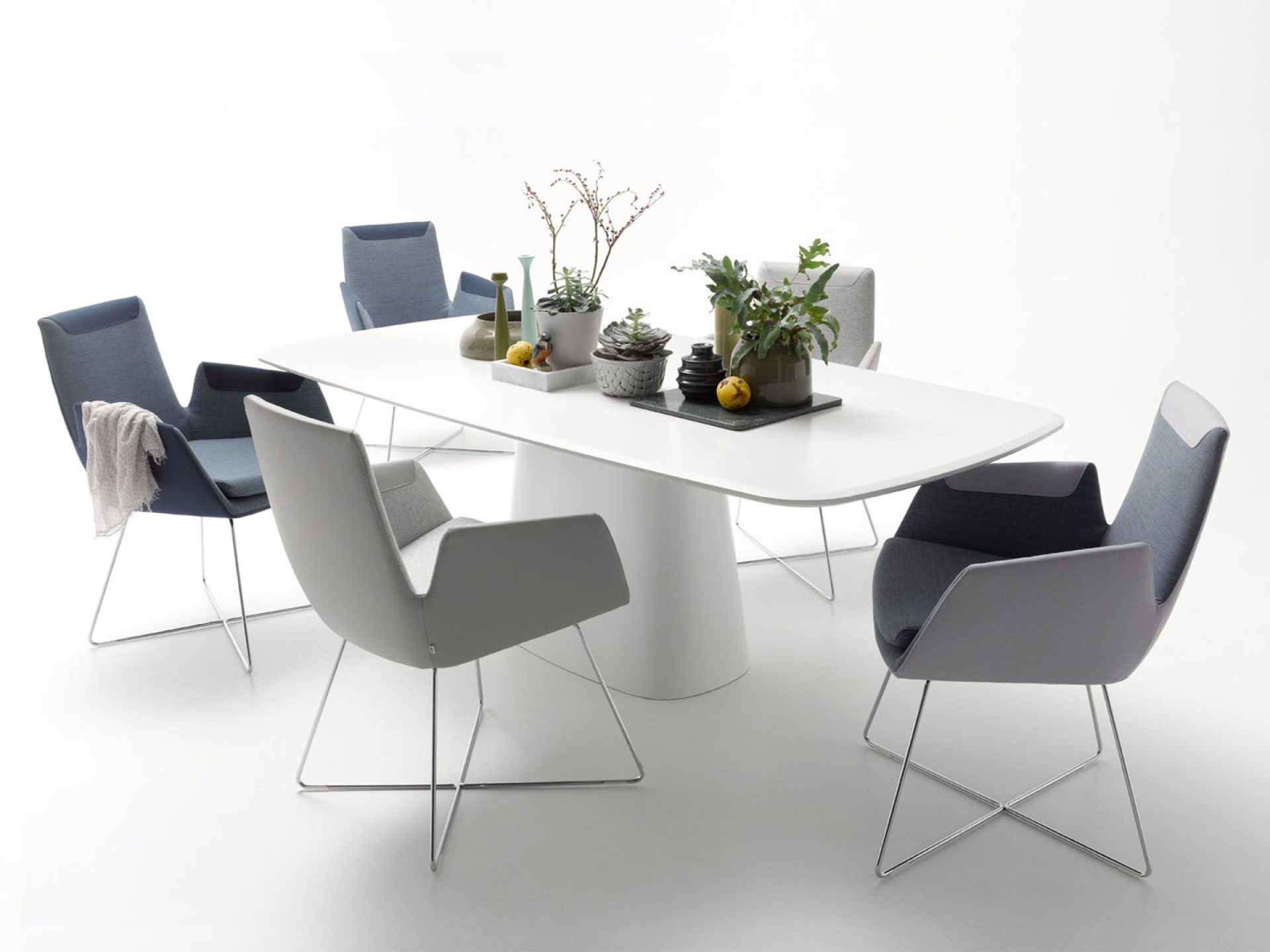 Weißer Conic Tisch mit Säulenfuß und sechs modernen Stühlen in Grau- und Blautönen.