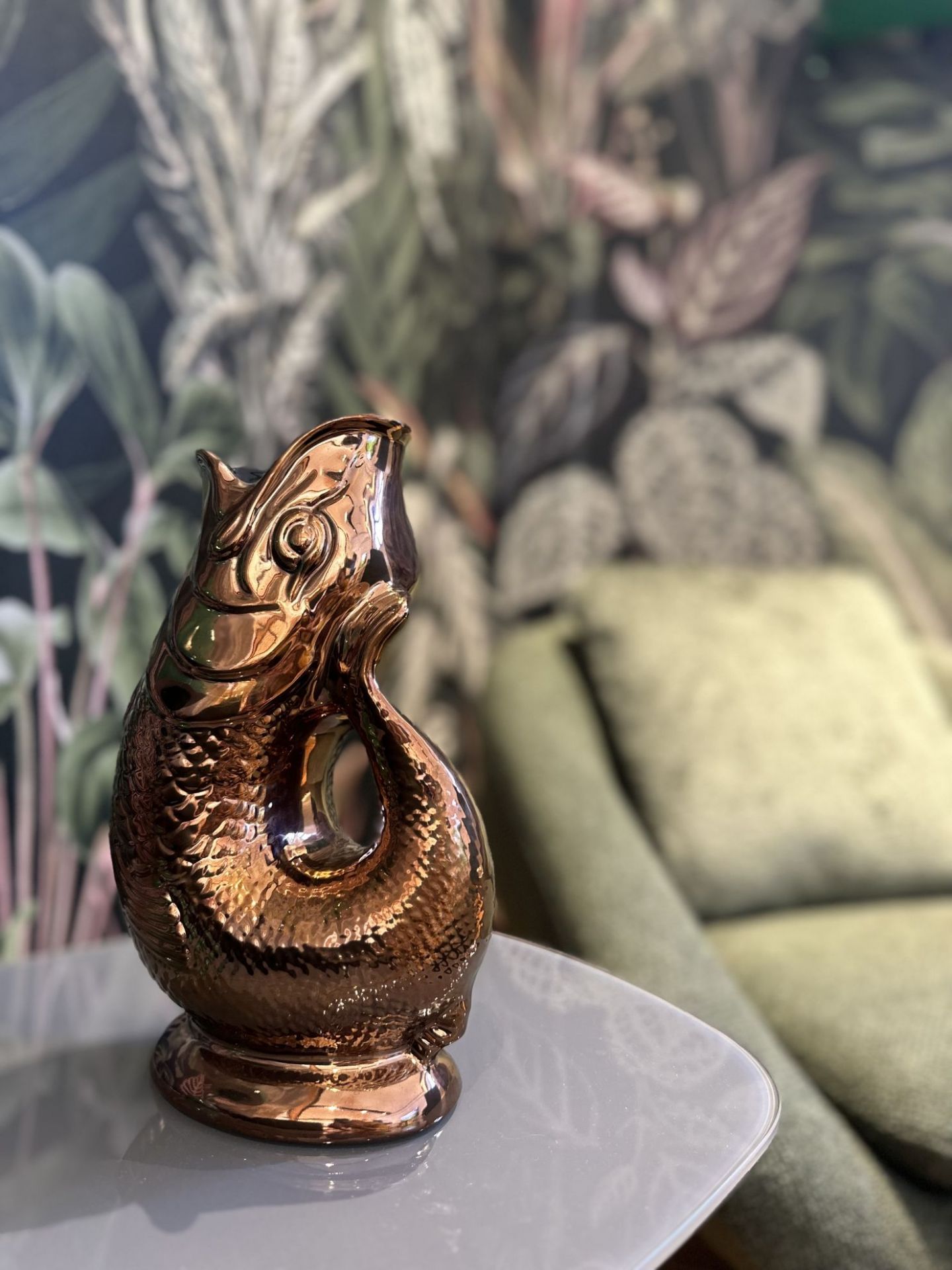 Kupferfarbene Gluckigluck Fischkaraffe auf einem Tisch, dekorative Wasserkaraffe im Fischdesign.