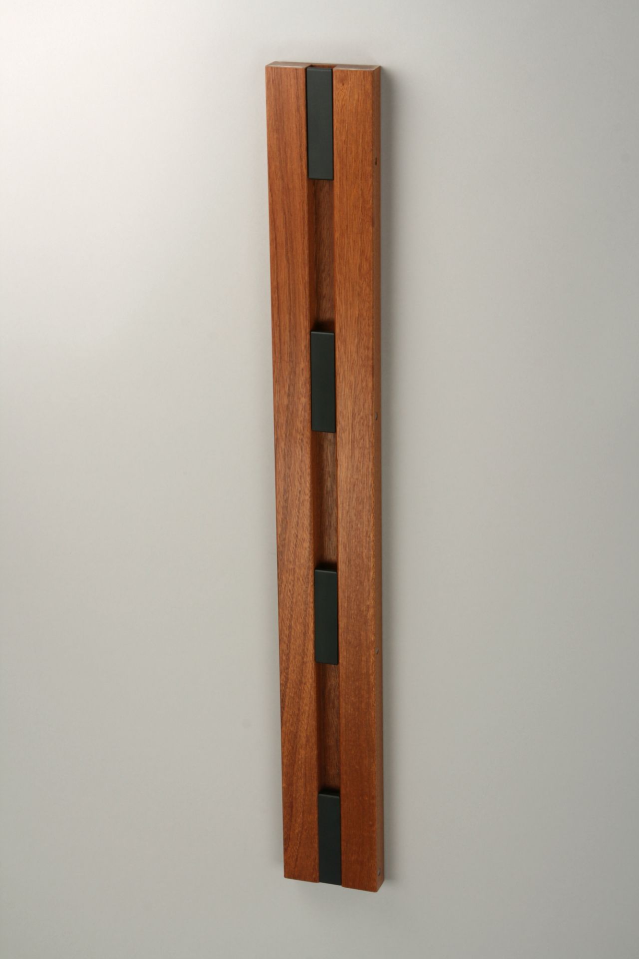 Knax Wandgarderobe mit vier schwarzen Haken an vertikaler Mahagoni-Holzleiste, ideal für Flur und Diele.