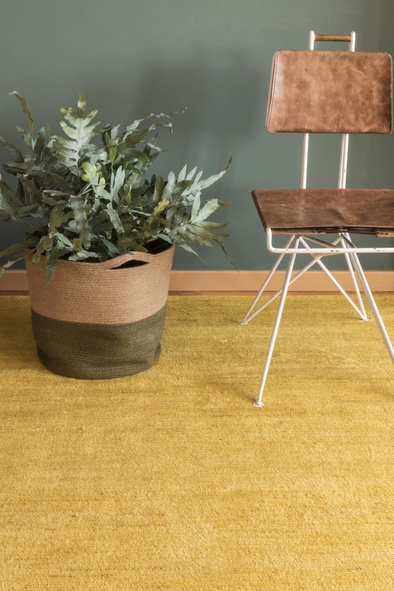 Nanimarquina Persian Colors Teppich in Gelb, Detailaufnahme mit Stuhl und Pflanze. Hochwertiger Wollteppich.