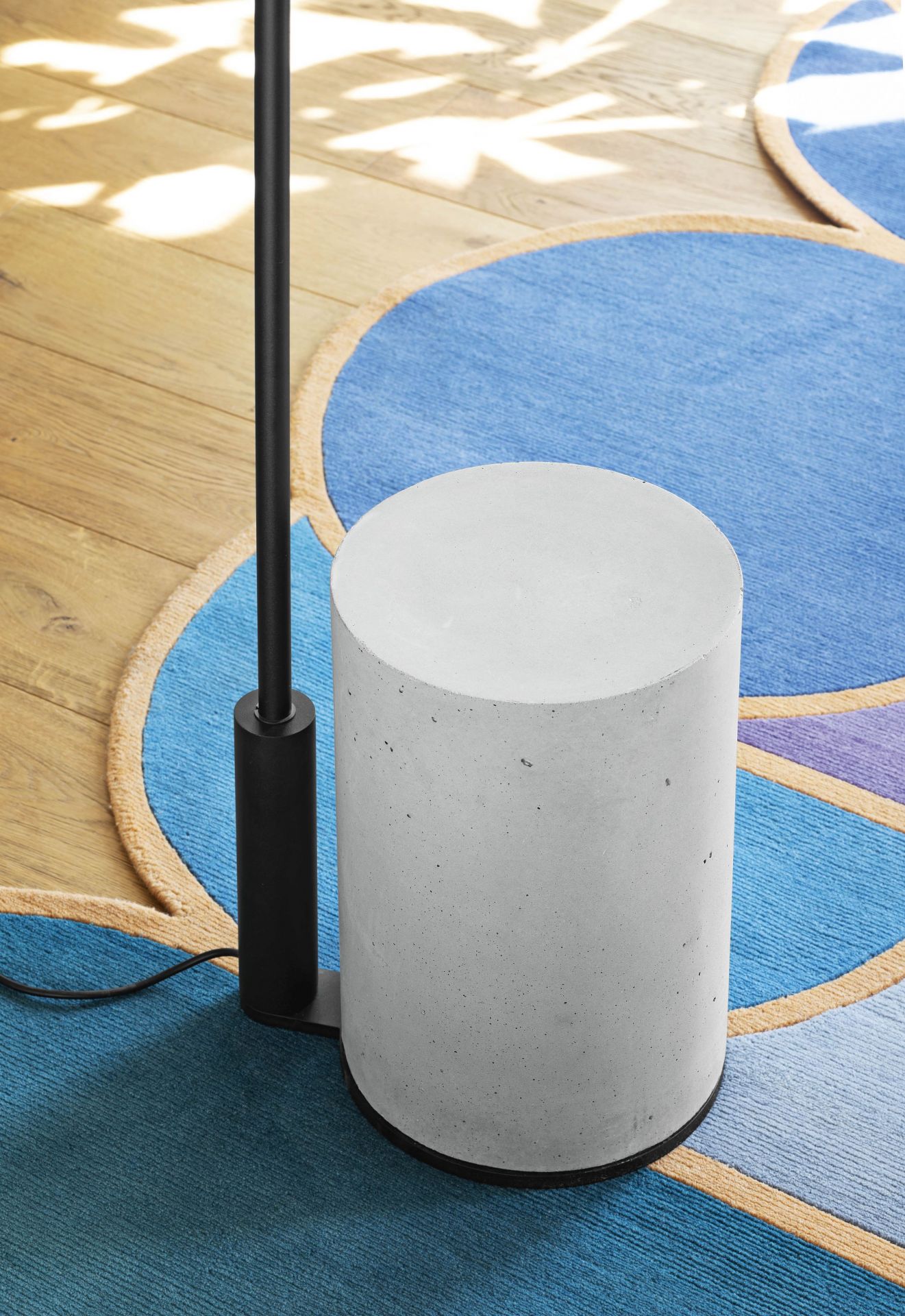 Ozz Floor Bodenleuchte von Miniforms: Moderne Stehlampe mit Betonfuß auf blauem Teppich.