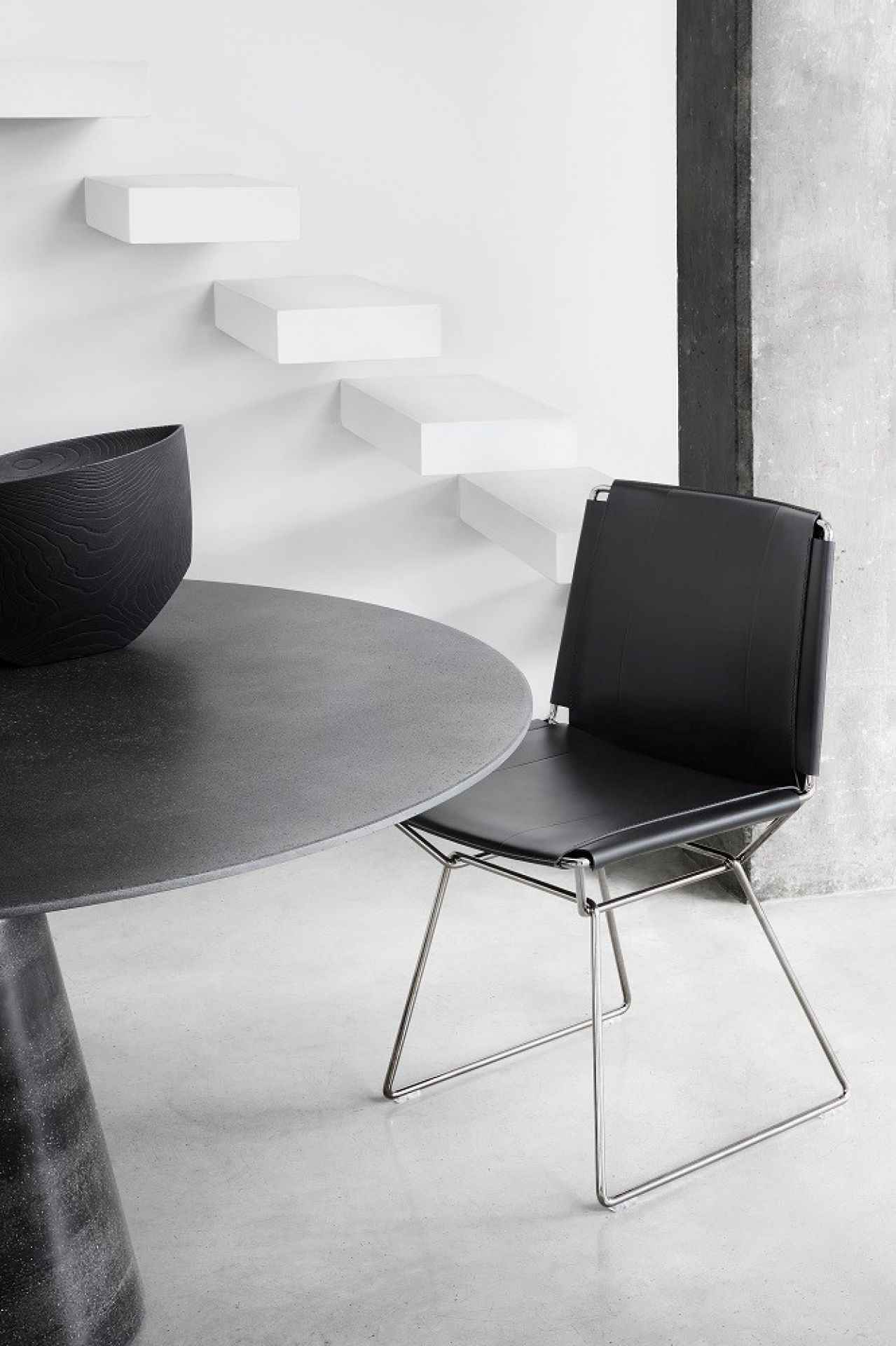Schwarzer Lederstuhl mit Metallgestell neben einem Esstisch. Moderner Design Stuhl.