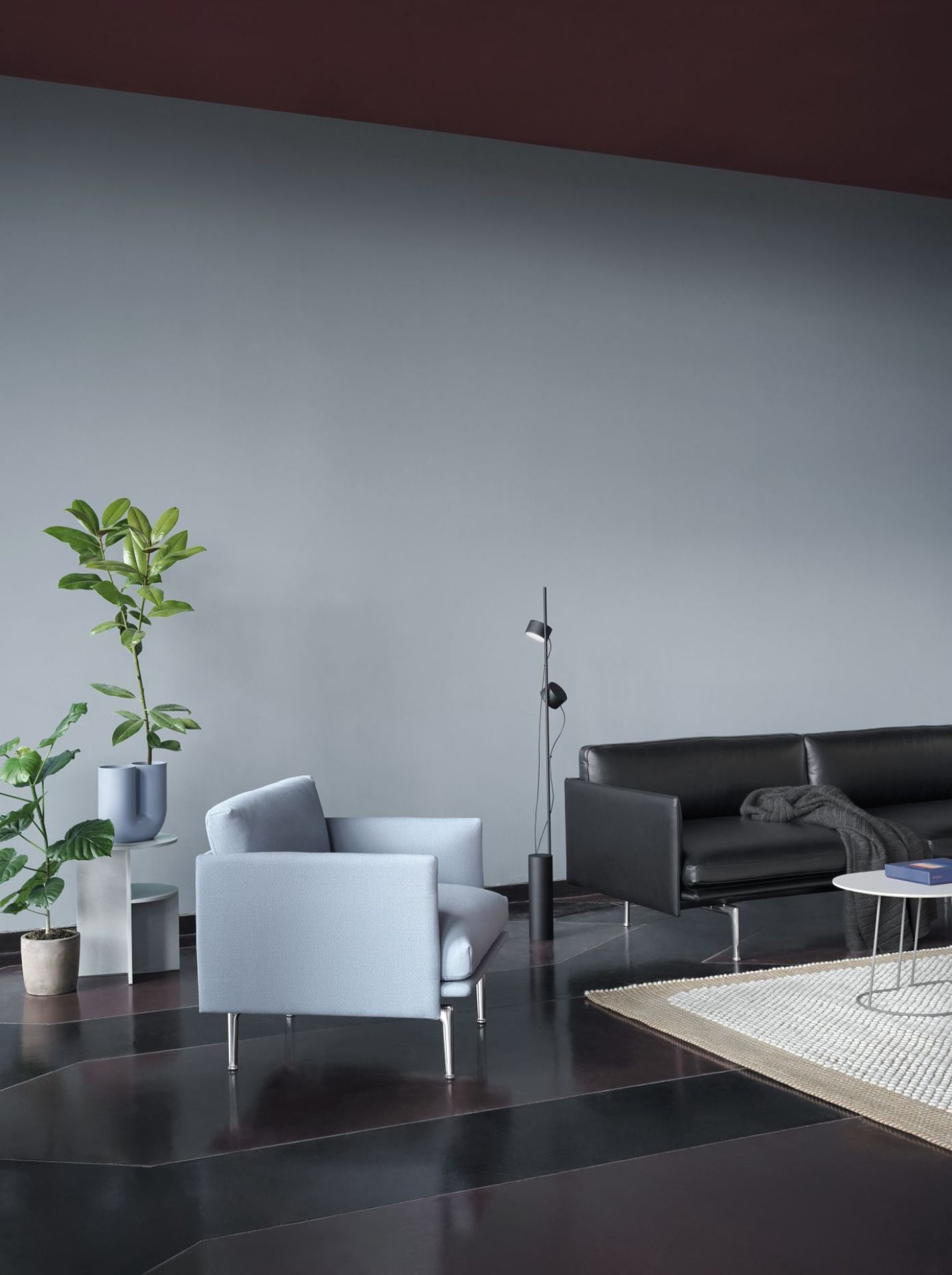 Wohnzimmer mit Muuto Ample Throw Decke in Dunkelgrau auf schwarzem Ledersofa. Gemütliches Wohnambiente.