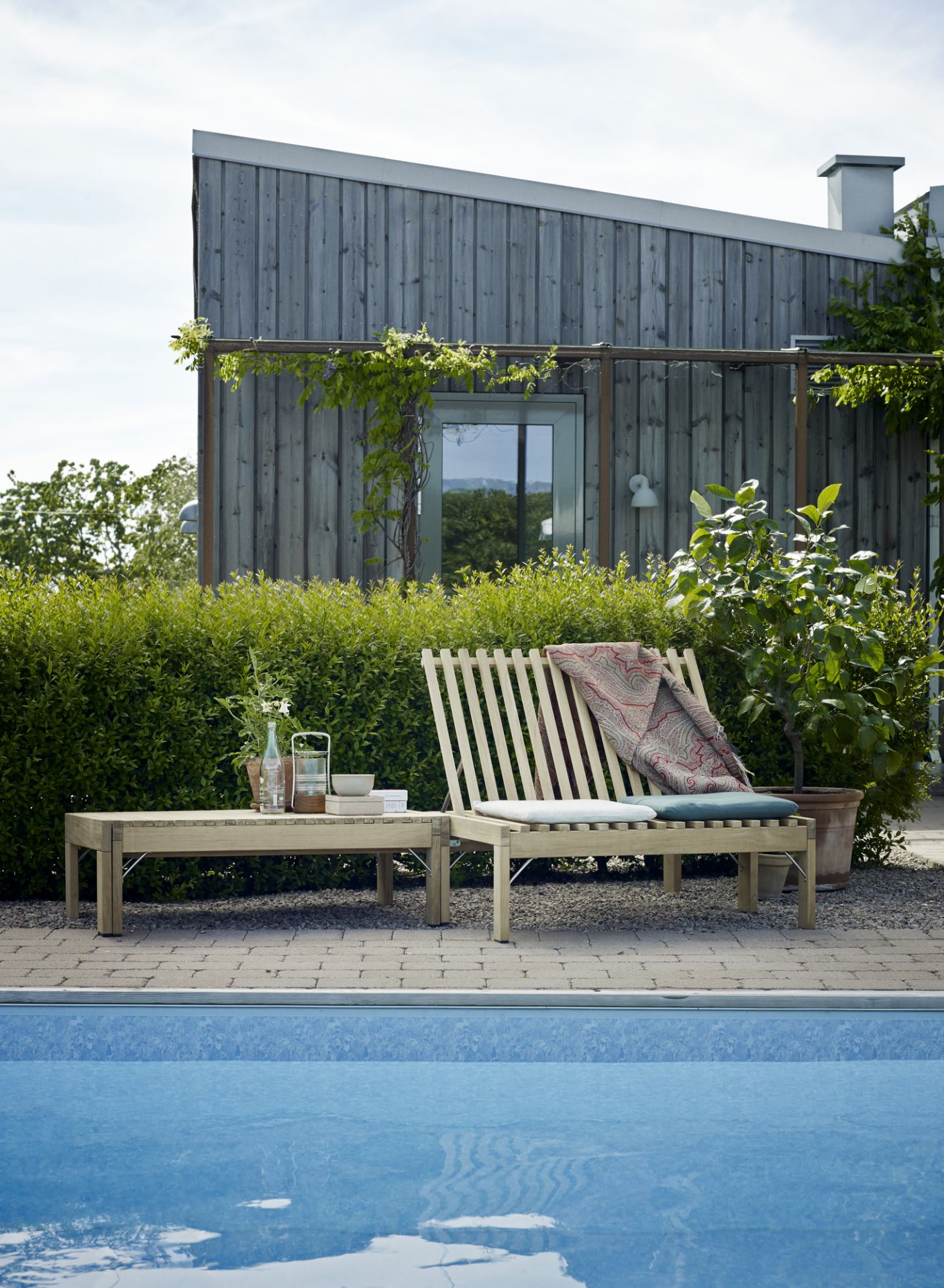 Riviera Lounge Teak Outdoor mit Sitzkissen und Beistelltisch am Pool. Gartenmöbel von Skagerak.