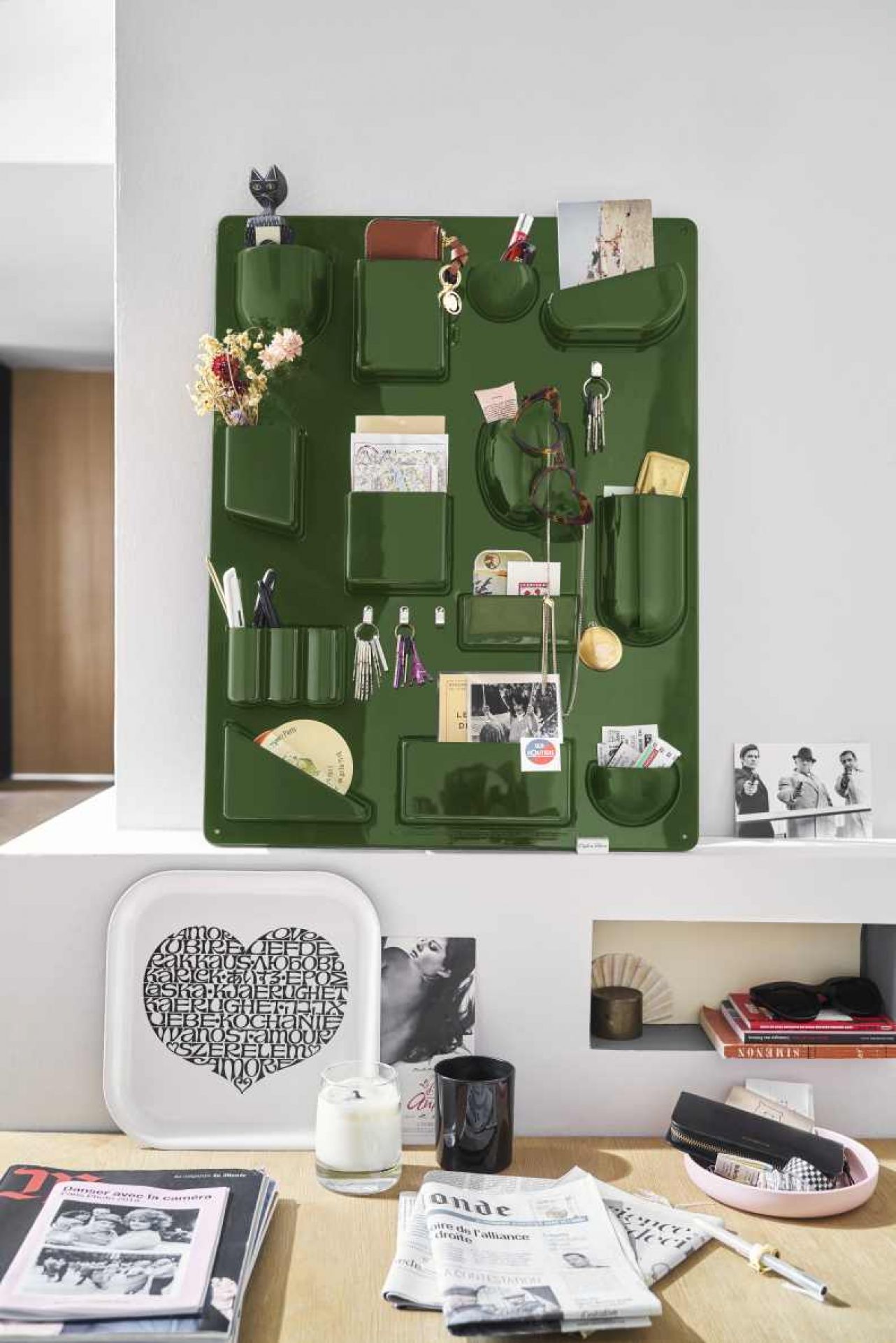 Detailaufnahme des grünen Vitra Uten.Silo Ordnungssystems an der Wand, gefüllt mit Büroartikeln und persönlichen Gegenständen.