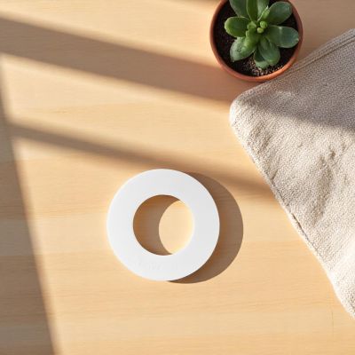 Weißer Dining Topfuntersetzer mit Hitzeschutz auf Holztisch, neben Pflanze und Tuch.