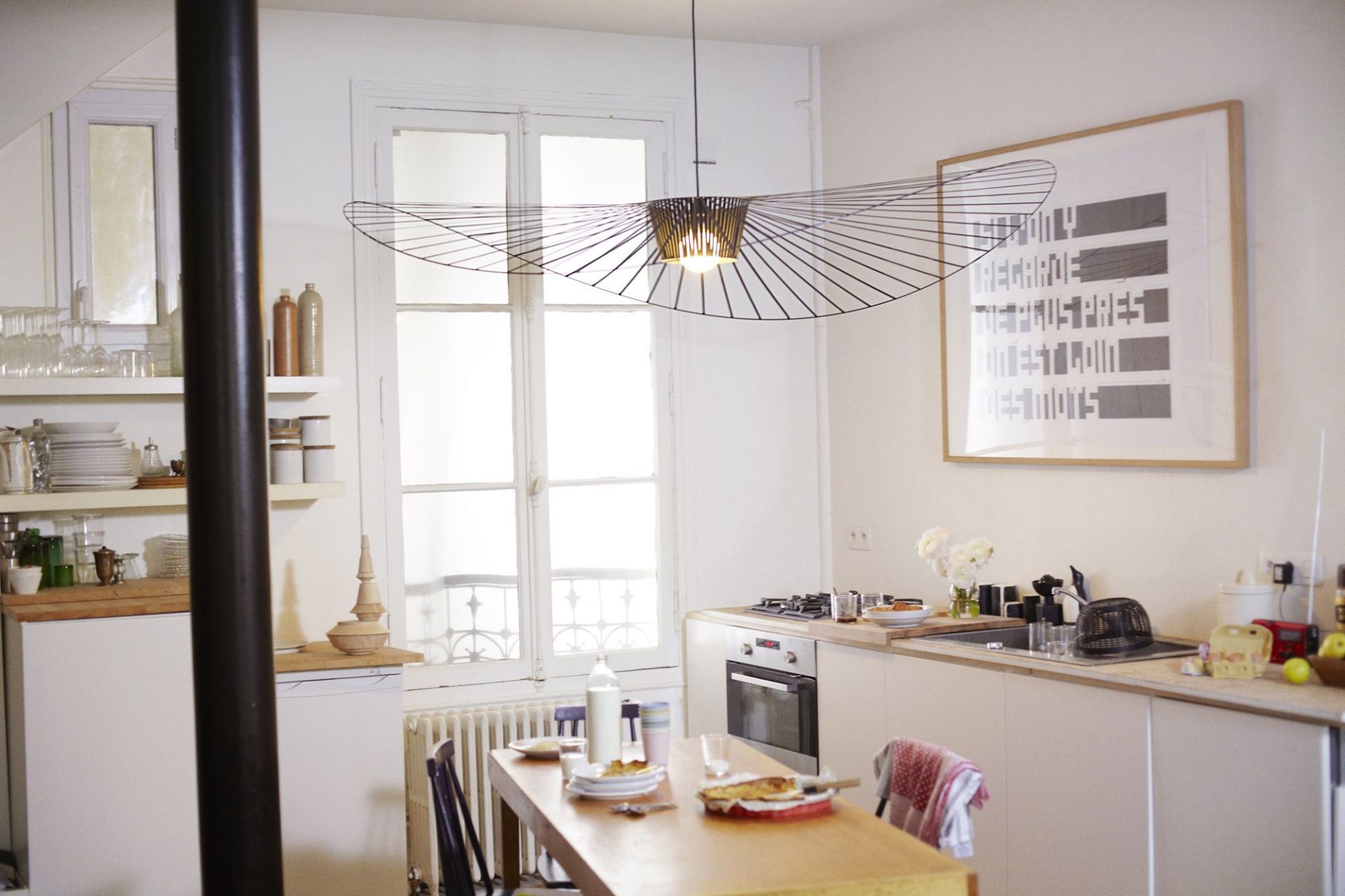 Weiße Vertigo Pendelleuchte von Petite Friture über Esstisch in heller Küche mit Fenster.