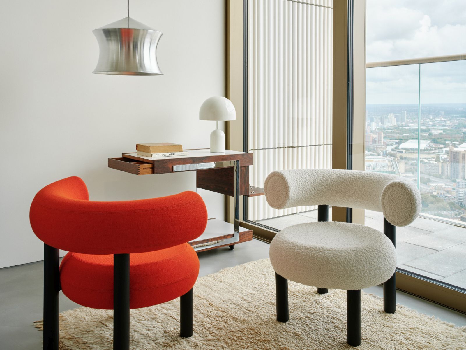 Nahaufnahme der Tom Dixon Unbeaten Waist Pendelleuchte über zwei modernen Sesseln in einem stilvollen Wohnzimmer.