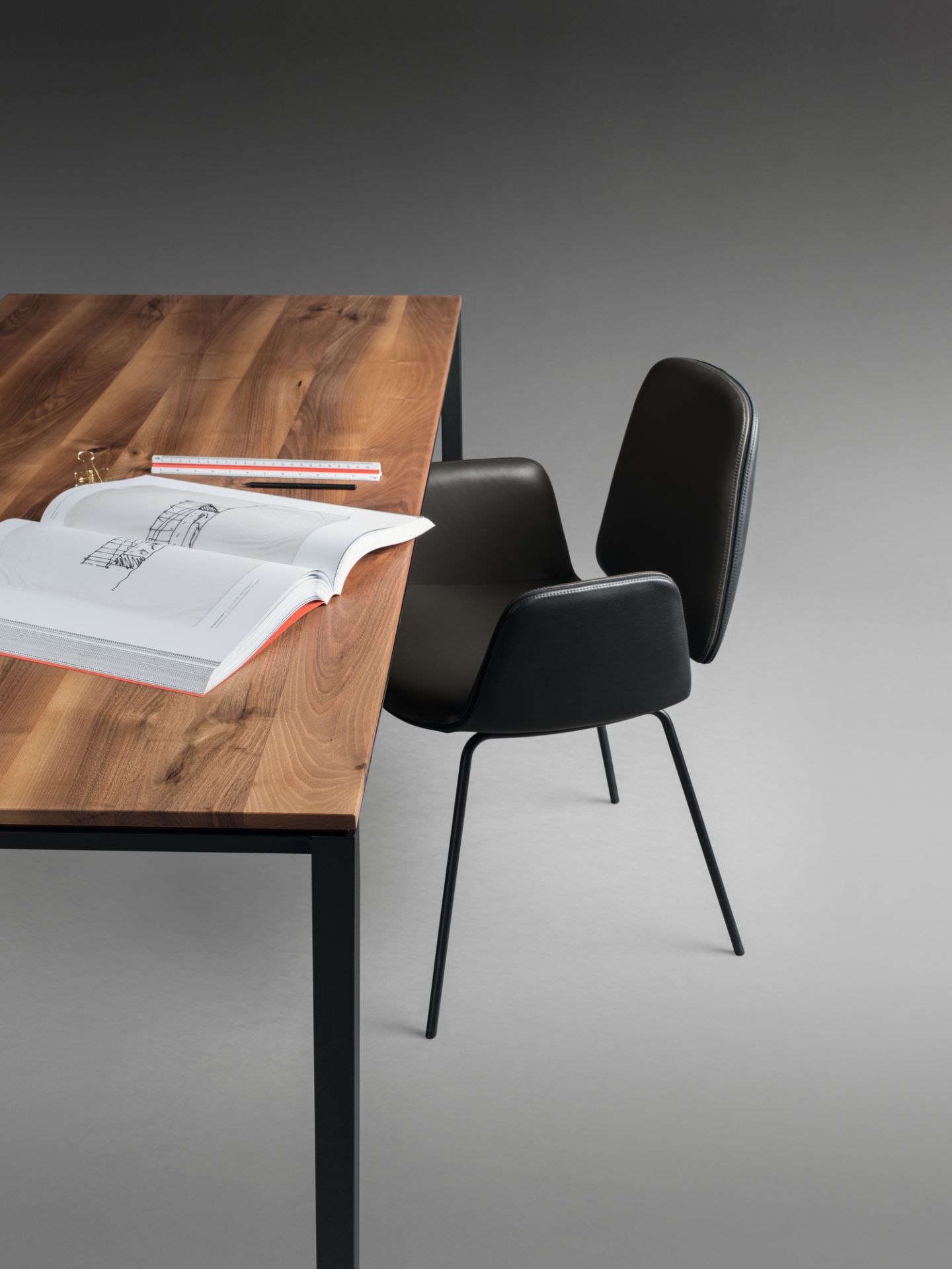 Detailaufnahme: Janua S 600 Tisch Nussbaum mit offenem Buch und Stuhl. Hochwertiger Esstisch.