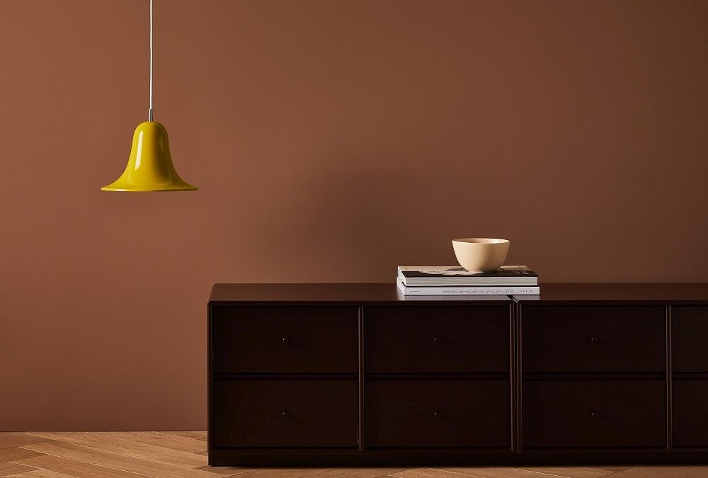 Gelbe Pantop Pendelleuchte von Verpan über brauner Kommode mit Schale und Büchern. Design Lampe.