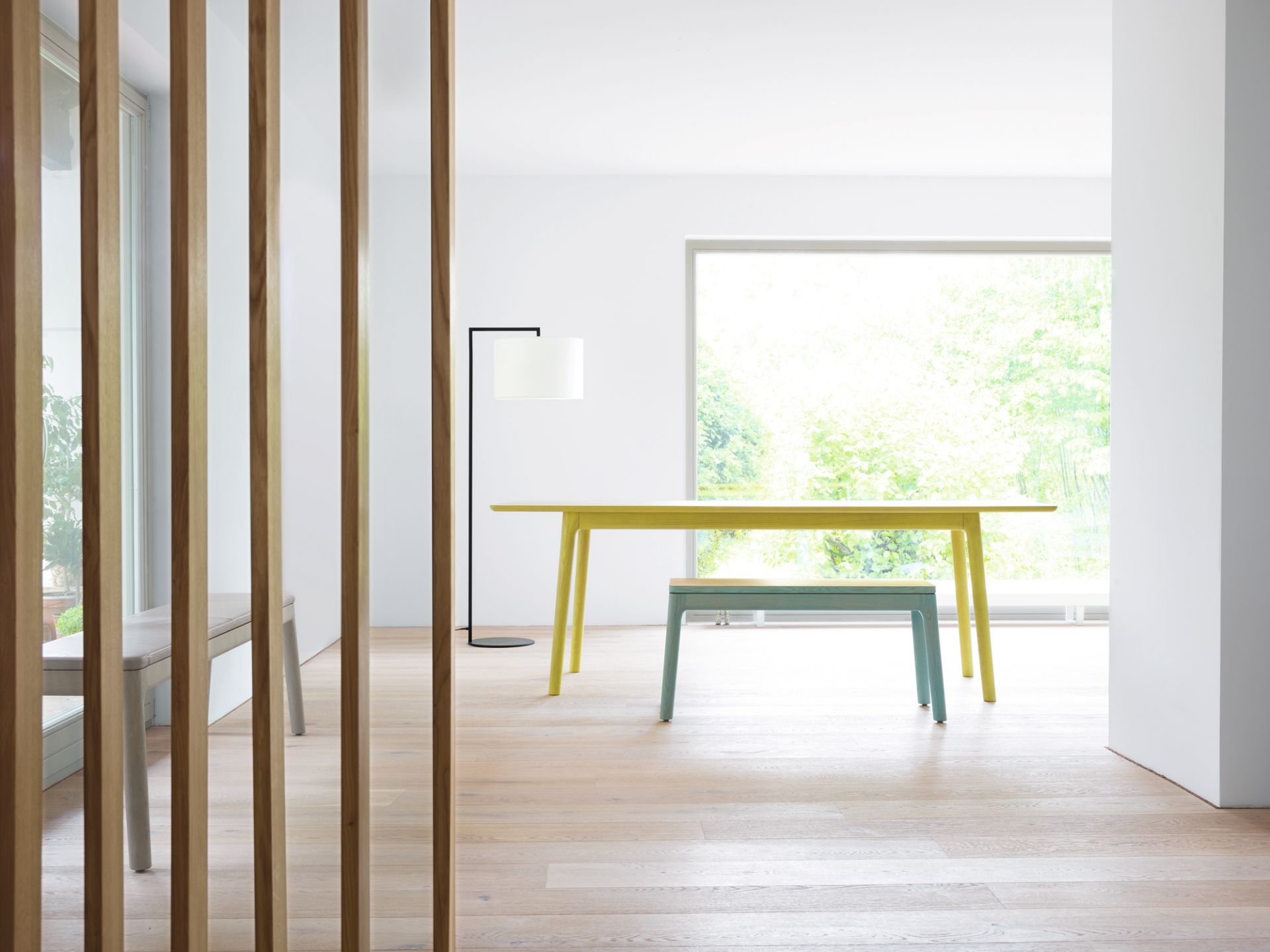 Helle, moderne Einrichtung mit Read Noon Stehleuchte, Tisch und Bank in minimalistischem Design.