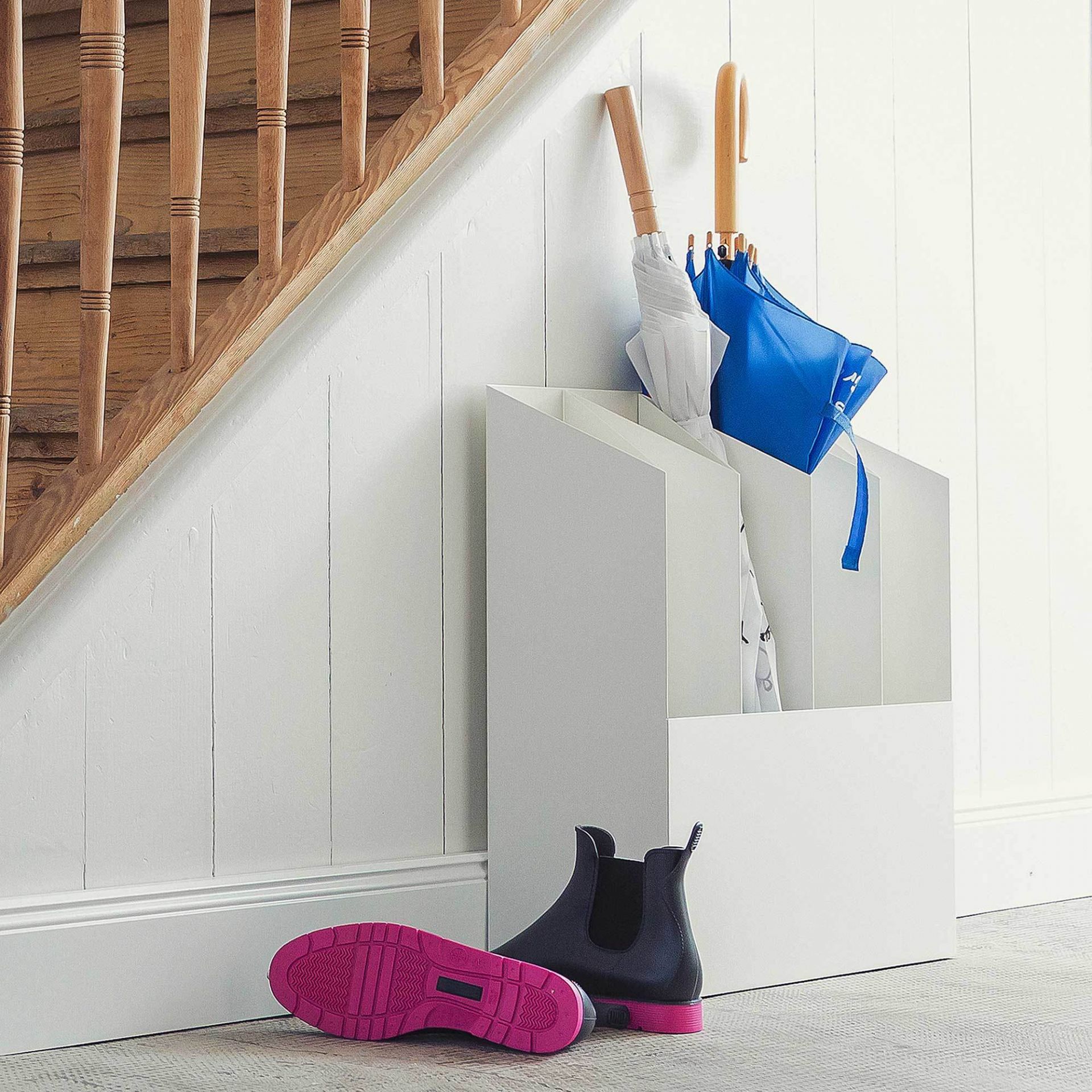 Weißer Kant Schirmständer mit Regenschirmen und Gummistiefeln im Flur. Moderner Schirmhalter für Ordnung.