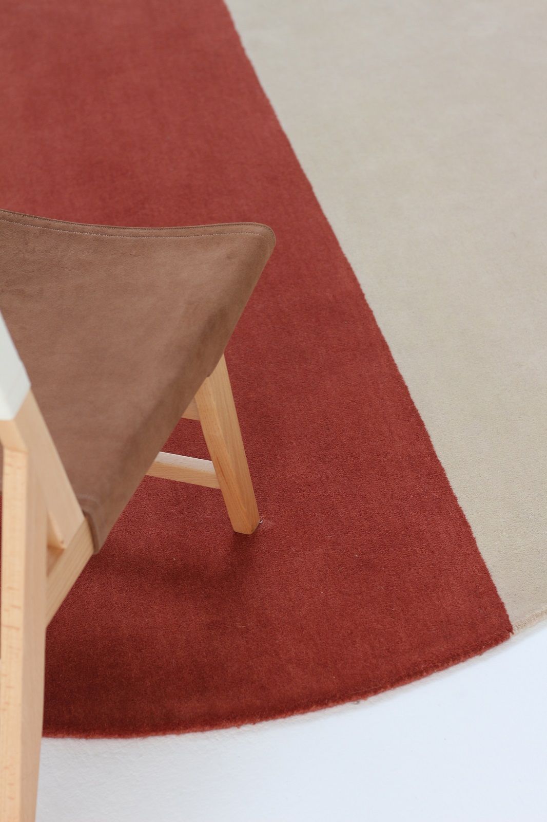 Detailaufnahme: Pearls Teppich von Nanimarquina, runder Wollteppich in Rot und Beige, mit Stuhl.