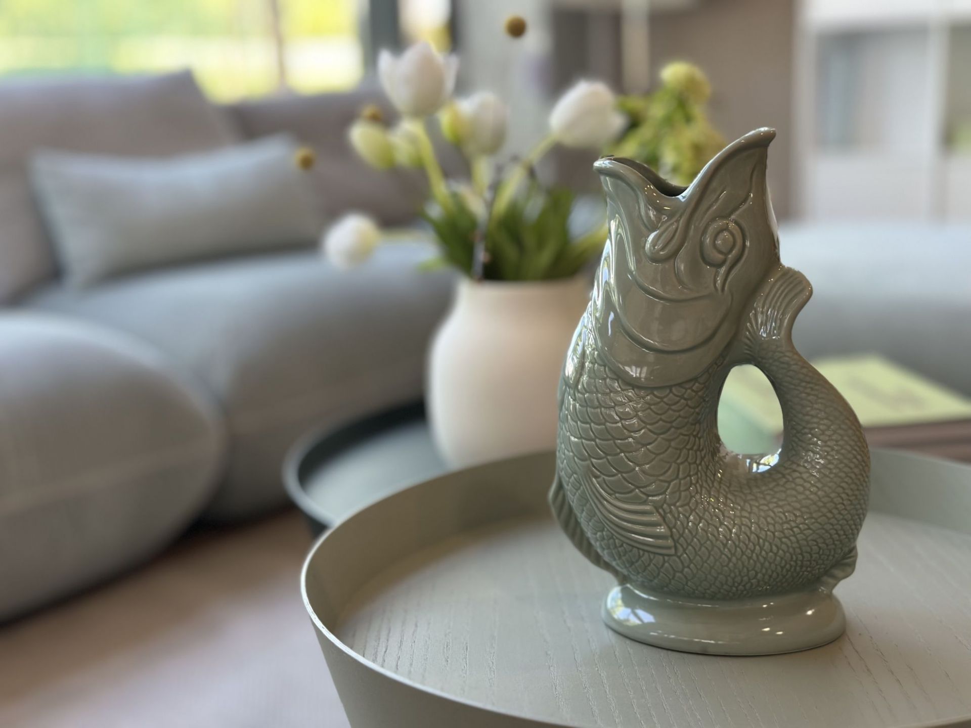 Gluckigluck Karaffe in Salbei-Grün XL auf einem Tisch. Dekorative Fisch-Karaffe für Wasser oder als Vase.