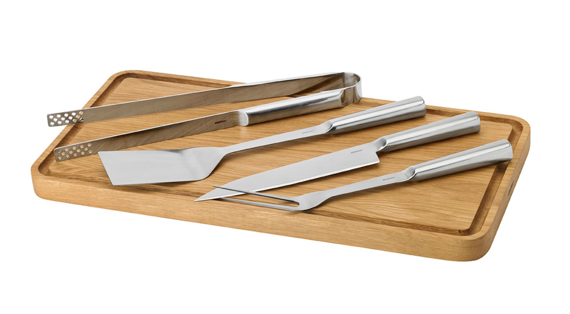 Stelton Grillbesteck Set auf Holzbrett: Grillzange, Wender, Messer und Gabel. Hochwertiges Grillzubehör.