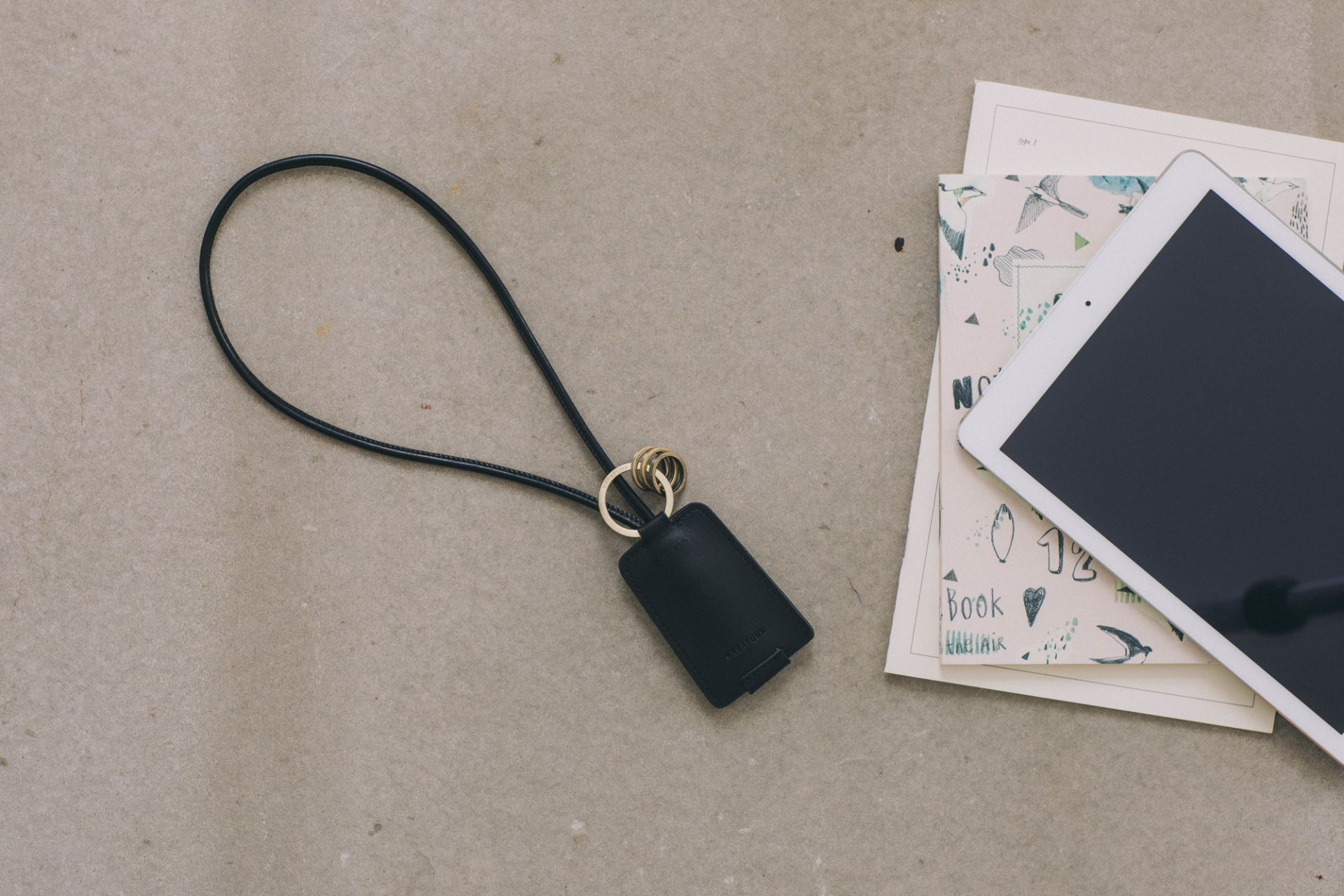 Schwarzer Kreafunk cCHAIN Schlüsselanhänger mit integriertem USB-Kabel, Lederband und goldenen Ringen.