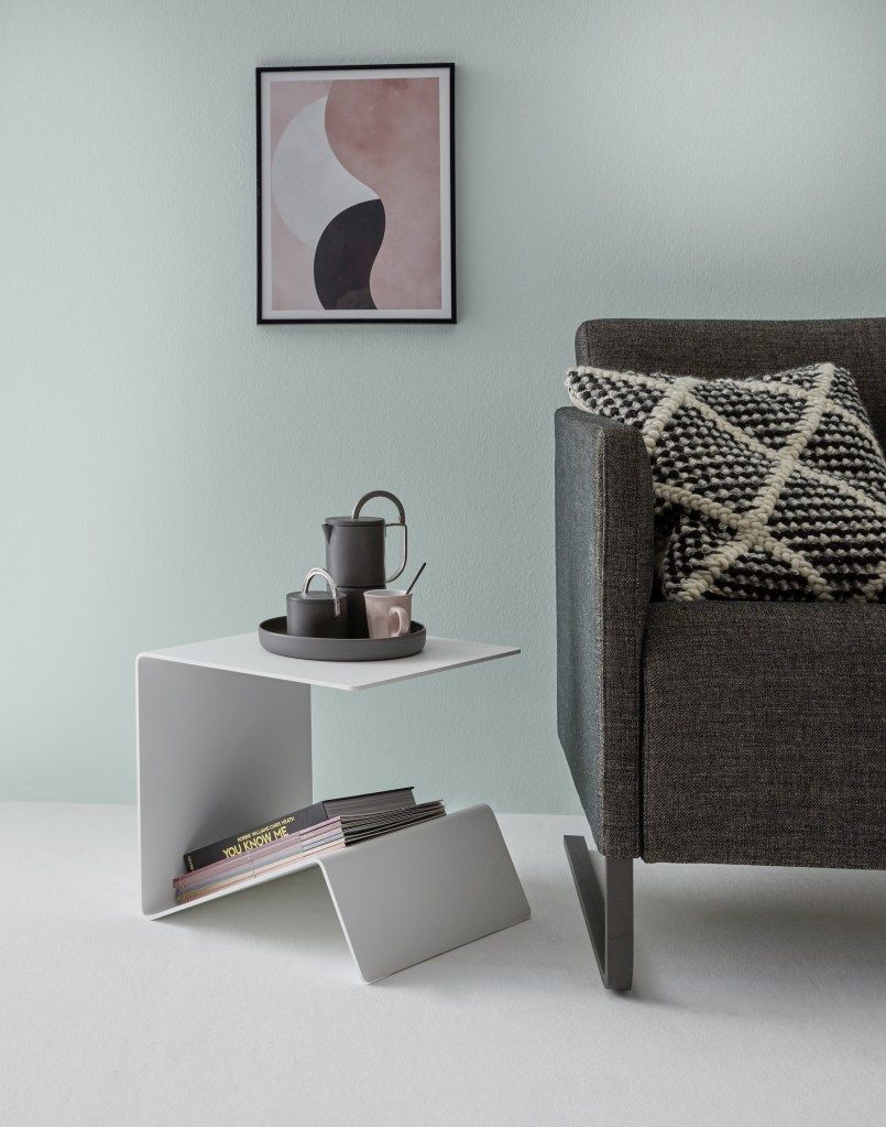 Weißer Buk Beistelltisch von Müller Möbelwerkstätten neben einem grauen Sessel mit Kissen.