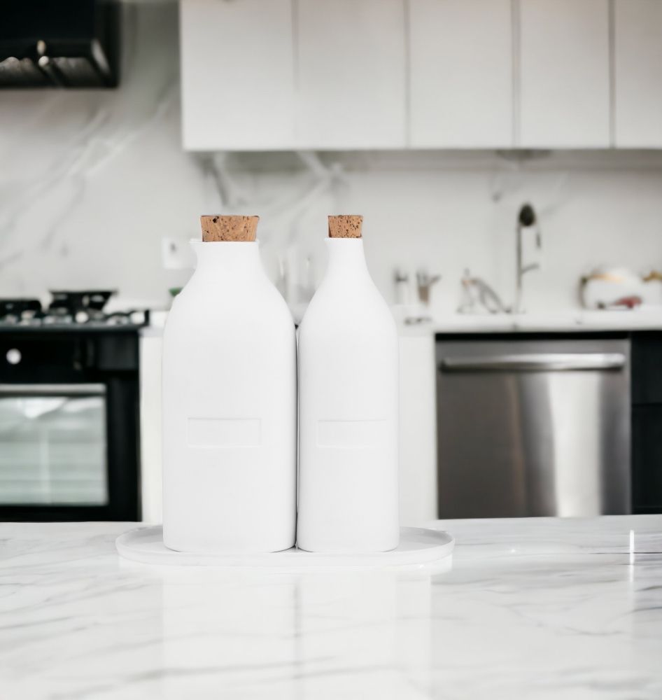 Zwei weiße Menage Flaschen mit Korken auf einem Marmortisch in einer Küche.