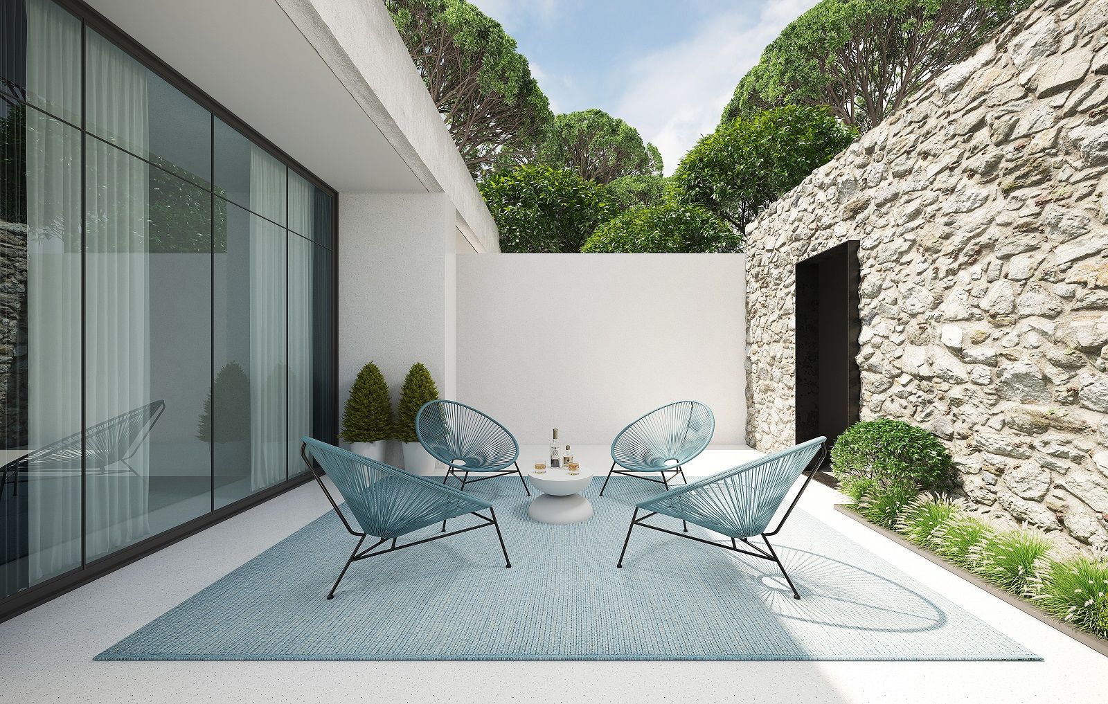 Vizoomy miinu Outdoor Teppich in Türkis auf Terrasse mit Stühlen und Steindekor. Wetterfester Teppich für Garten.