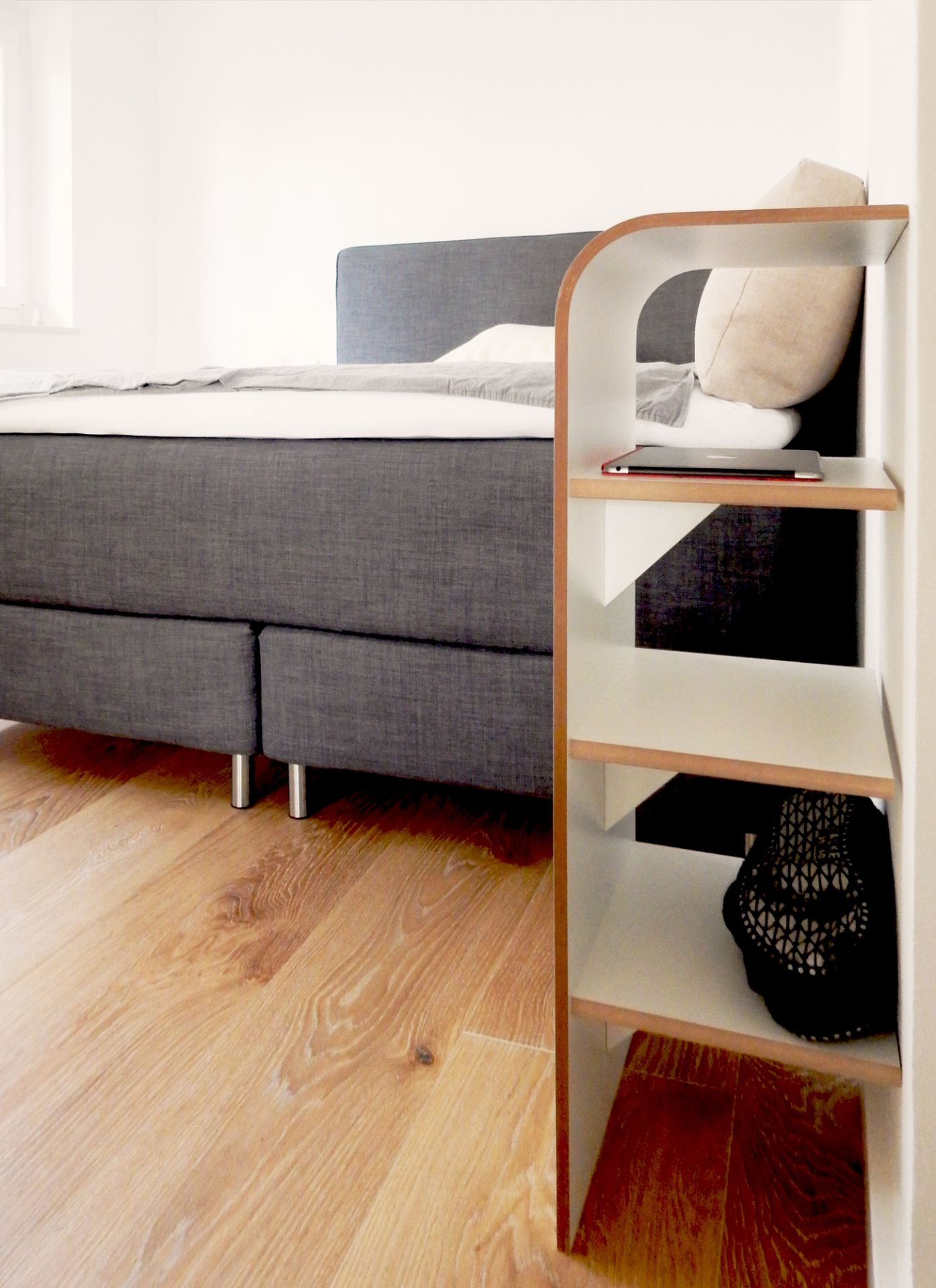 Tojo Regal aus Holz mit drei Ablageflächen, neben einem Bett stehend. Schuhregal für Schlafzimmer.