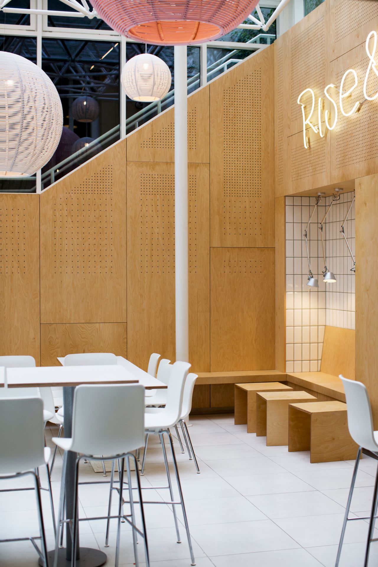 Helle Gastronomie mit weißen Hal Barhockern von Vitra an weißen Tischen.