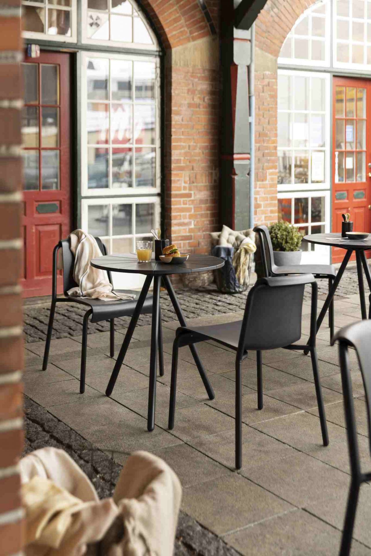 Schwarzer Nami Dining Chair Outdoor Stuhl von Houe an einem Tisch im Freien. Gartenmöbel für Terrasse.