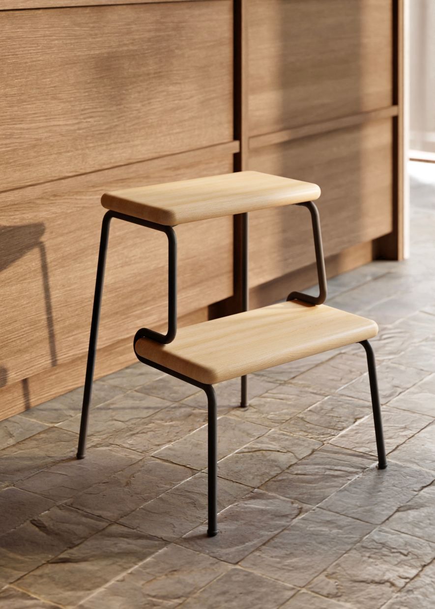 Slalom Step Stool Tritthocker: Moderner, zweistufiger Hocker aus hellem Holz und schwarzem Metall.