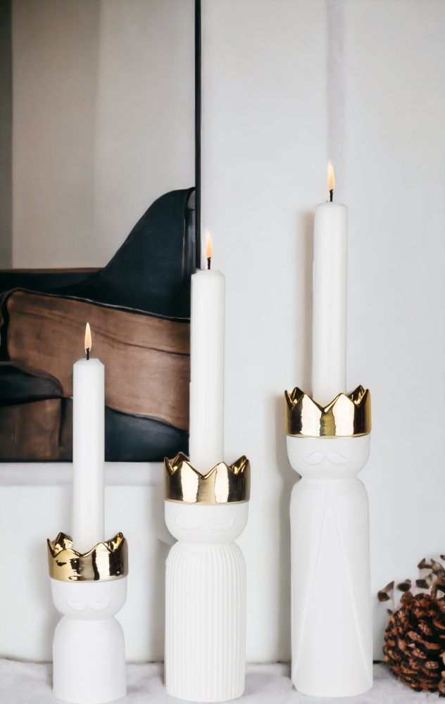 Königslicht Sortiment: Drei weiße Räder Kerzenständer mit goldener Krone und brennenden Kerzen. Dekorative Wohnaccessoires.