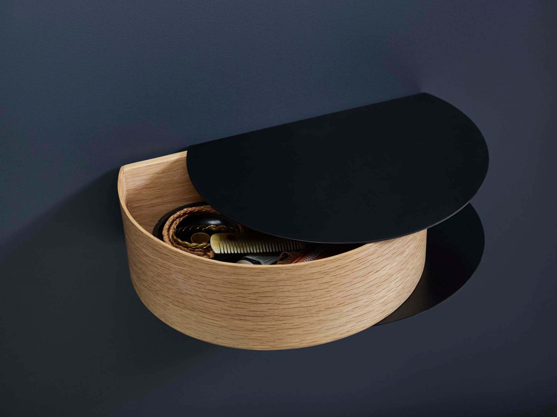 Wallie Wandschublade von Woud aus Eiche mit schwarzem Deckel, gefüllt mit persönlichen Gegenständen.