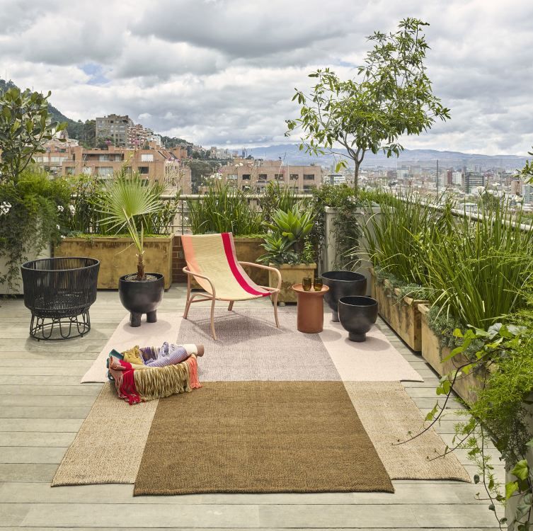 Nobsa Rug von ames: Großer, brauner Teppich auf einer Dachterrasse mit Möbeln und Pflanzen.