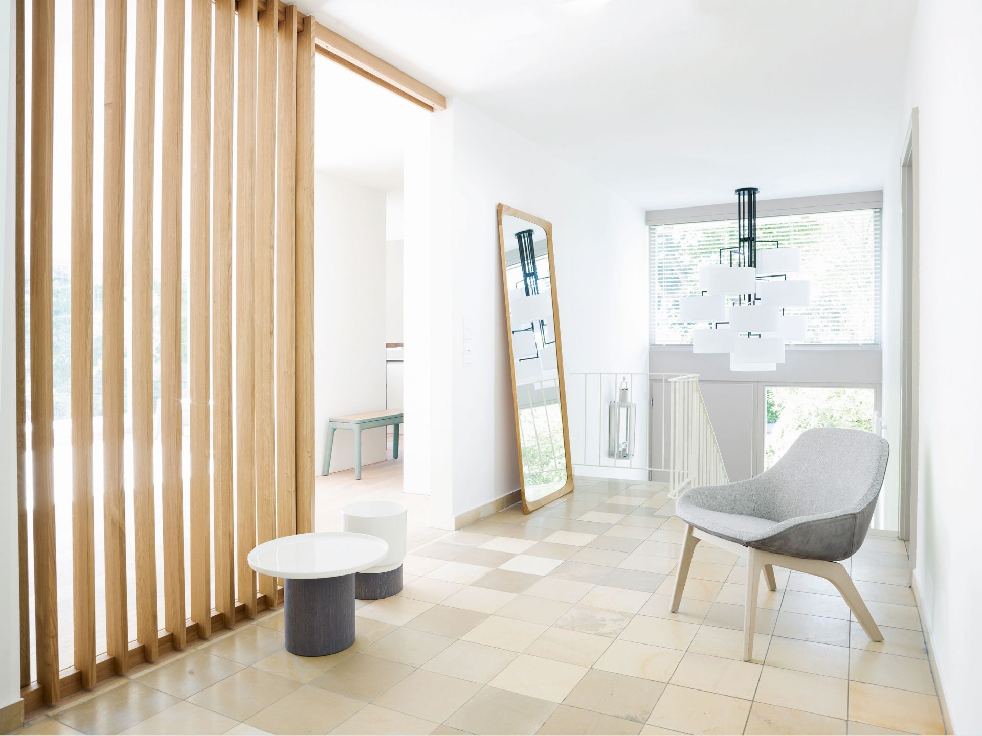 Heller Raum mit NOON 12 Deckenleuchte in Warmgrau, Stuhl und minimalistischer Einrichtung.